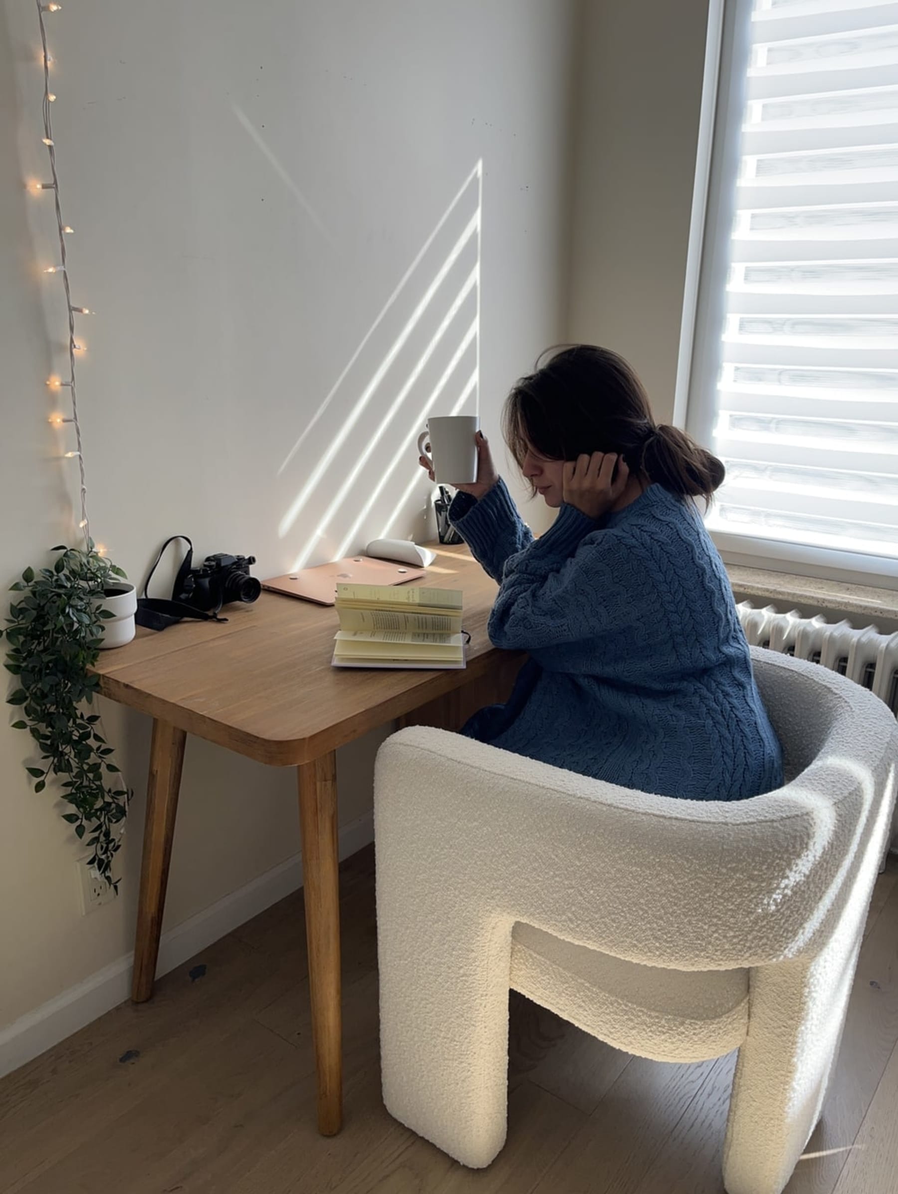 A person is reading a book at a wooden desk.