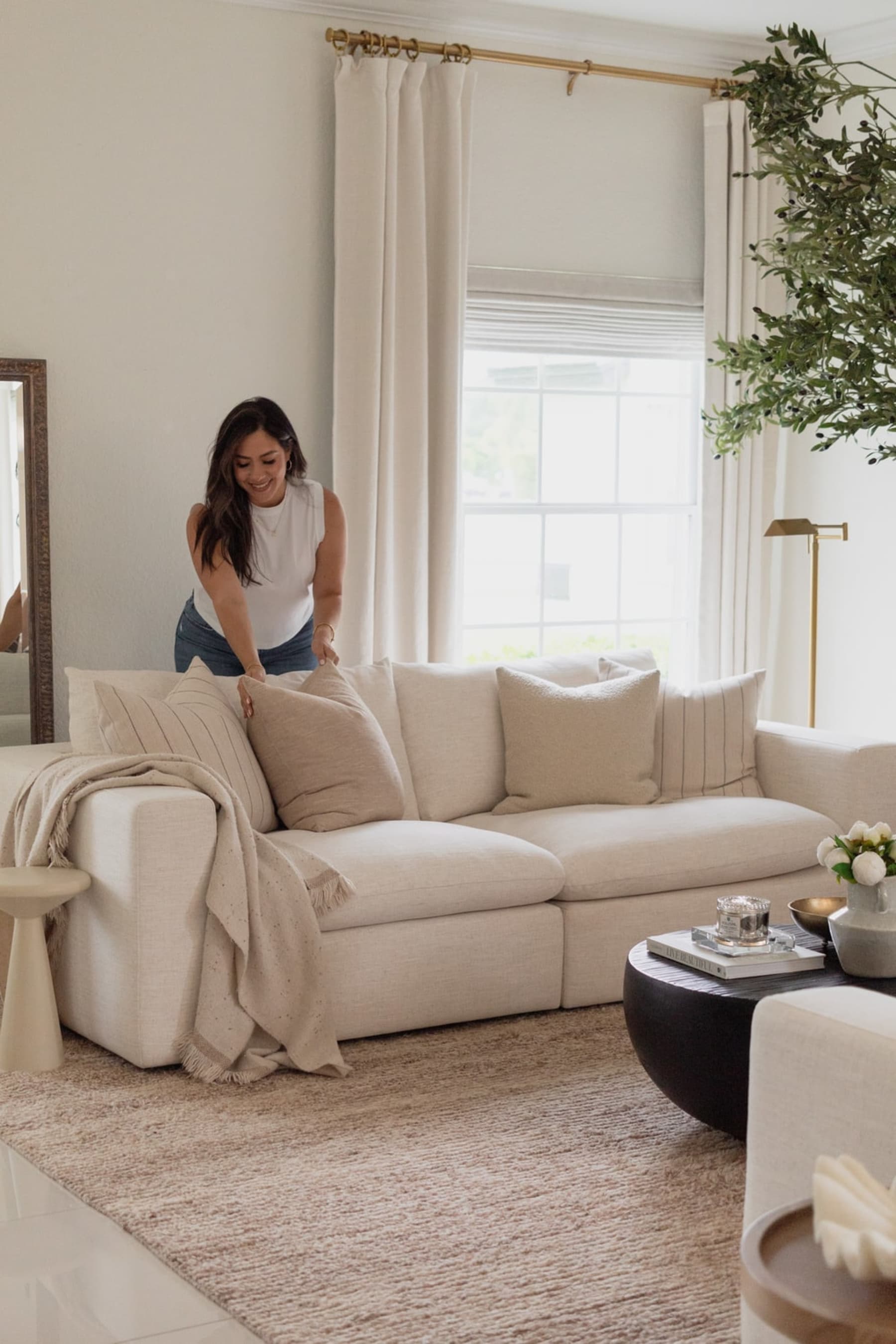 A person is fluffing the cushions on the sofa.