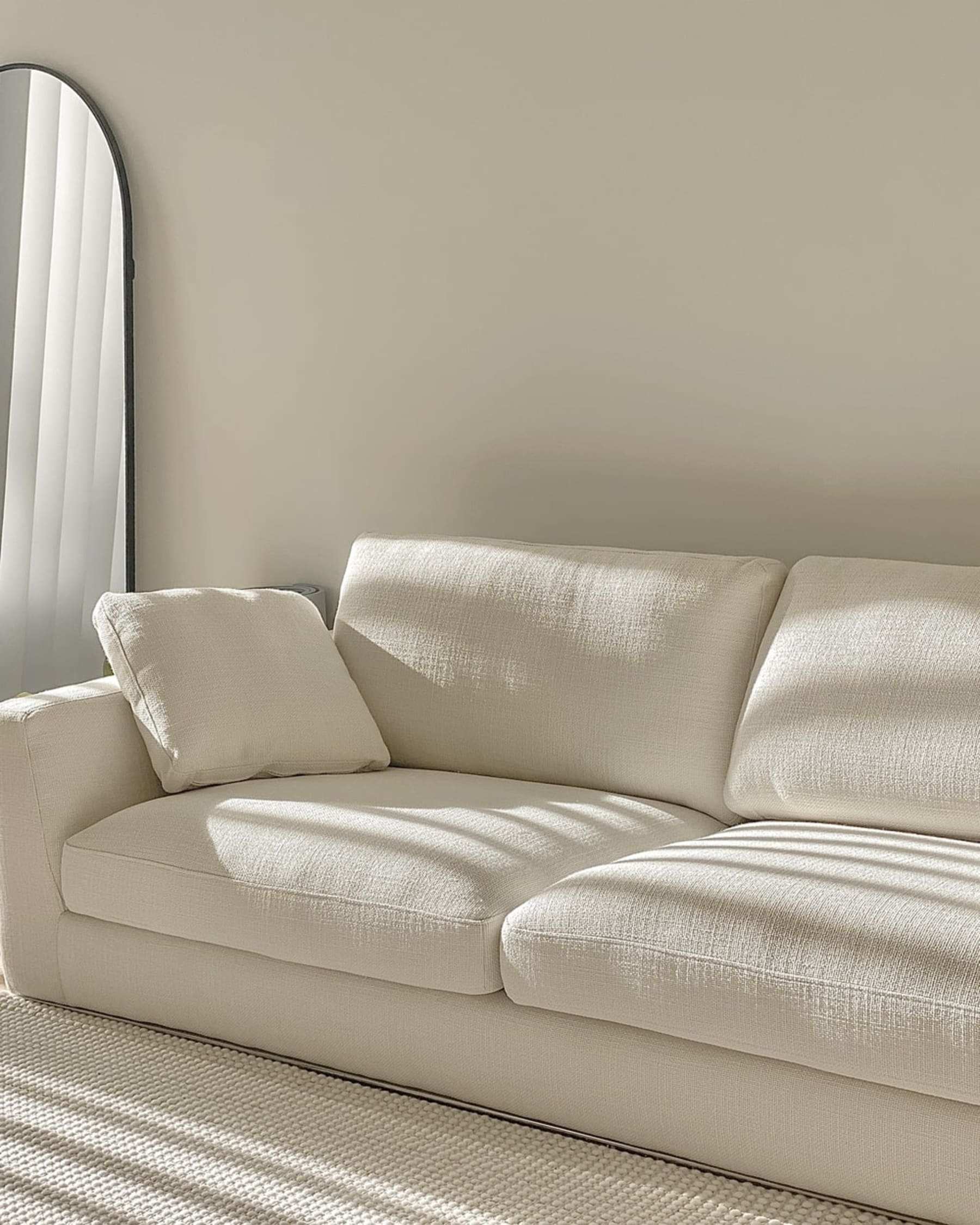 A white fabric sofa with sun rays cast on the seats.