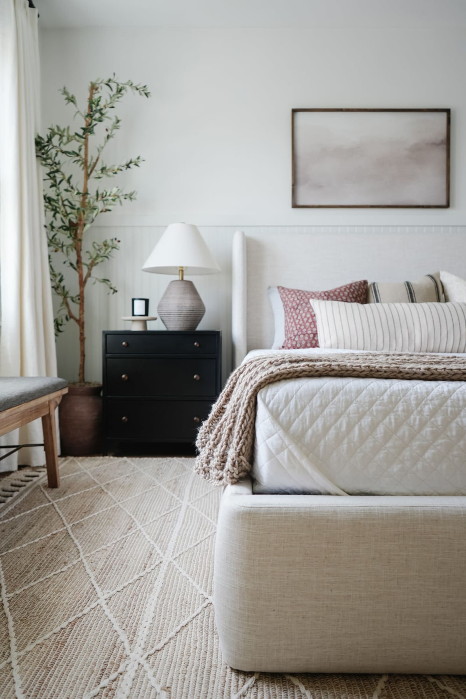 A jute area rug anchors the bed in a bedroom.