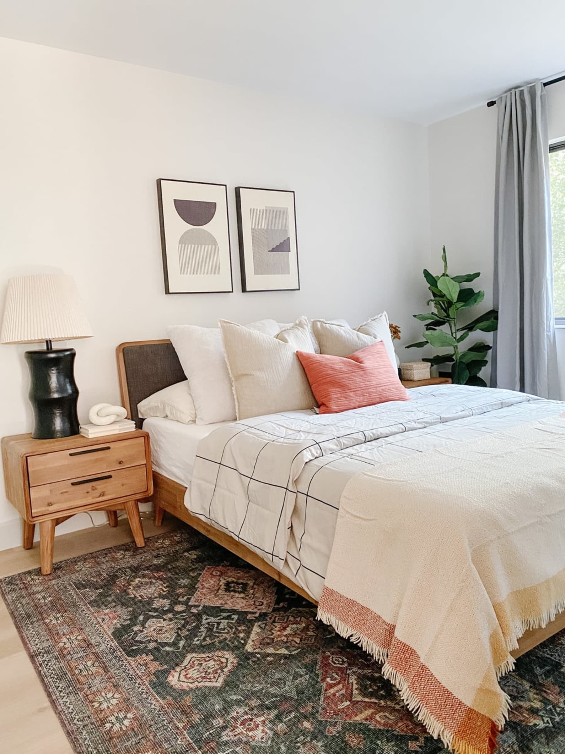 A wooden bed with patterned sheets and a throw.