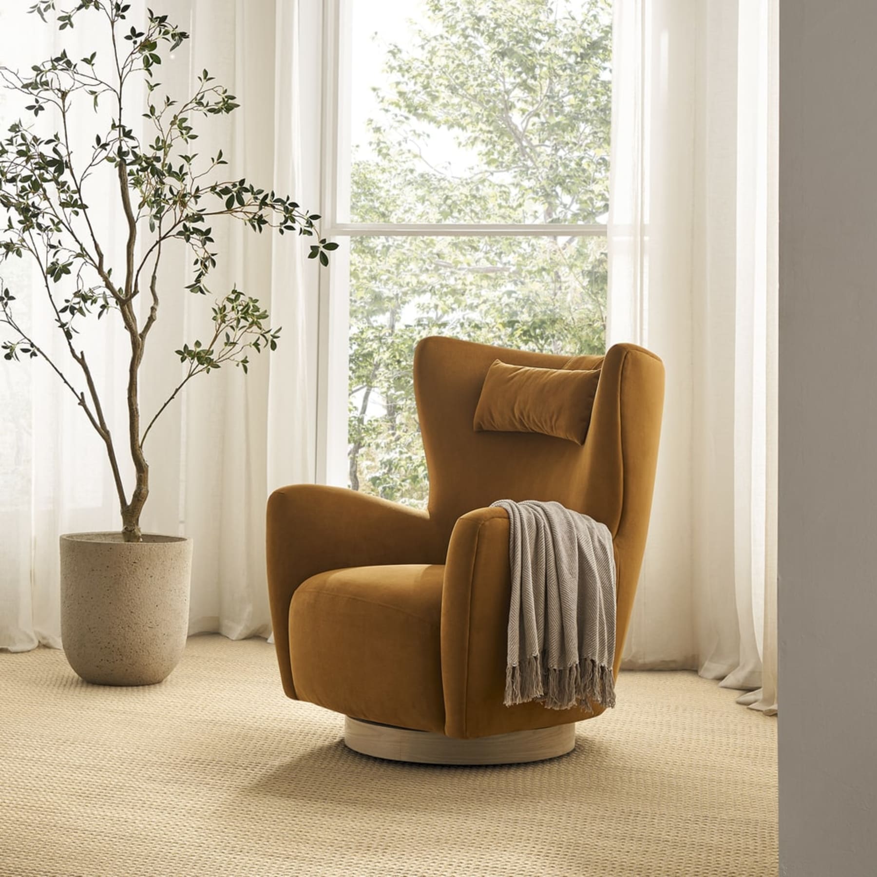 A swivel armchair in a mustard yellow shade beside a window.