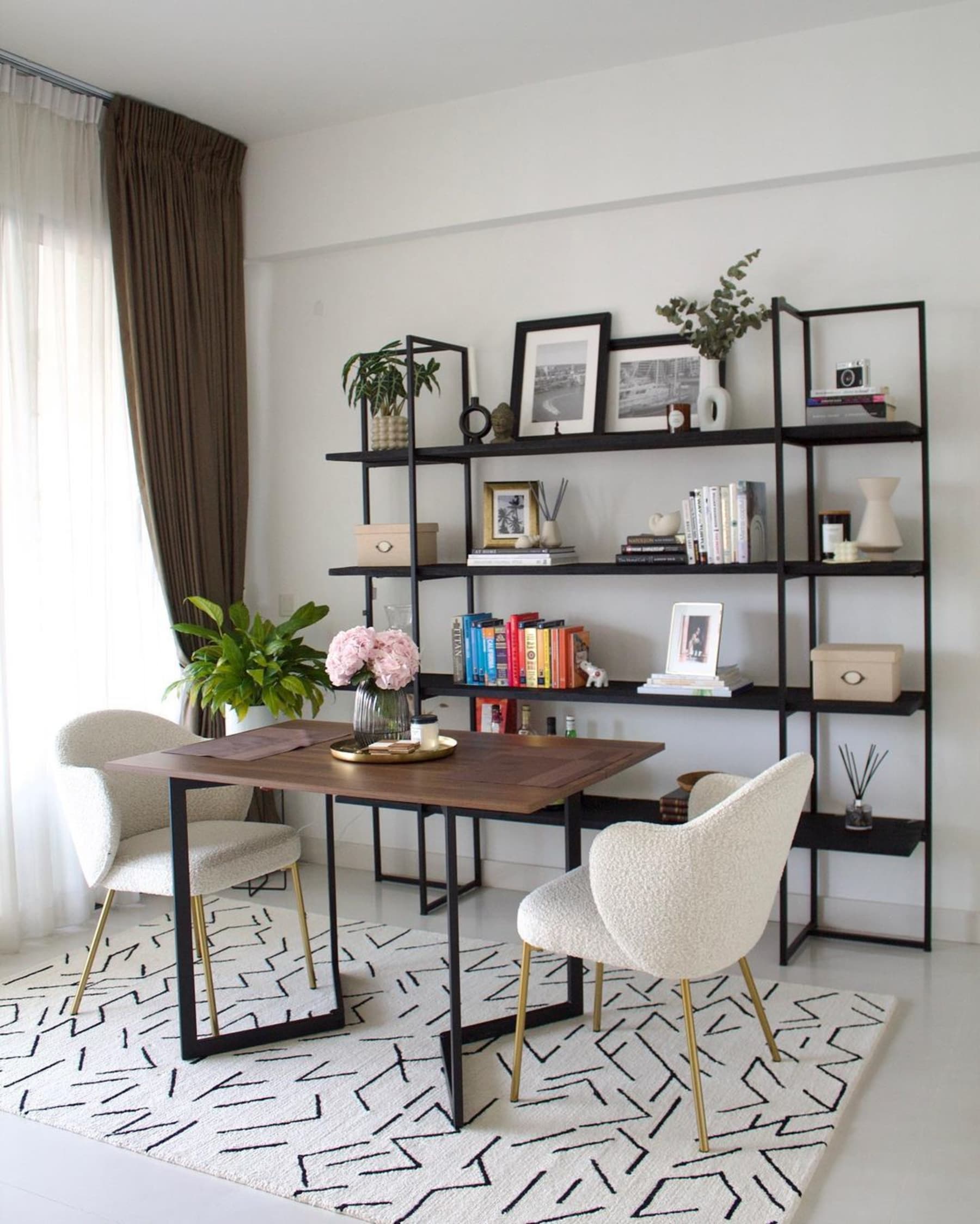 2 armchairs and a table sit atop a wool area rug.