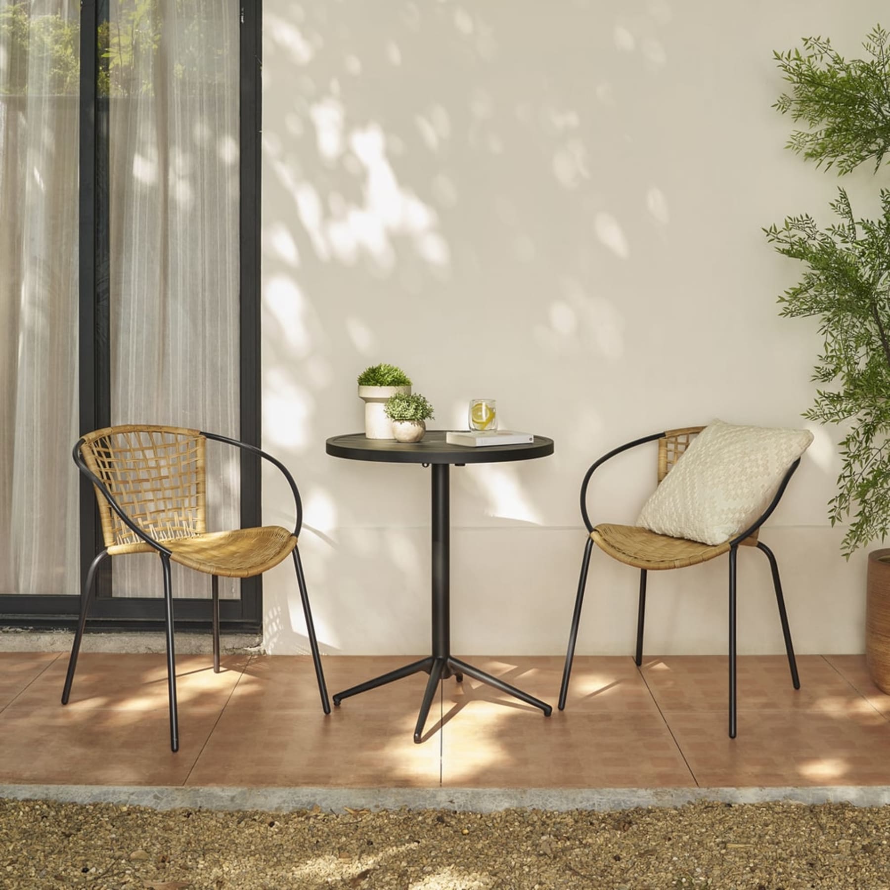 An aluminum foldable bistro table with rattan chairs.