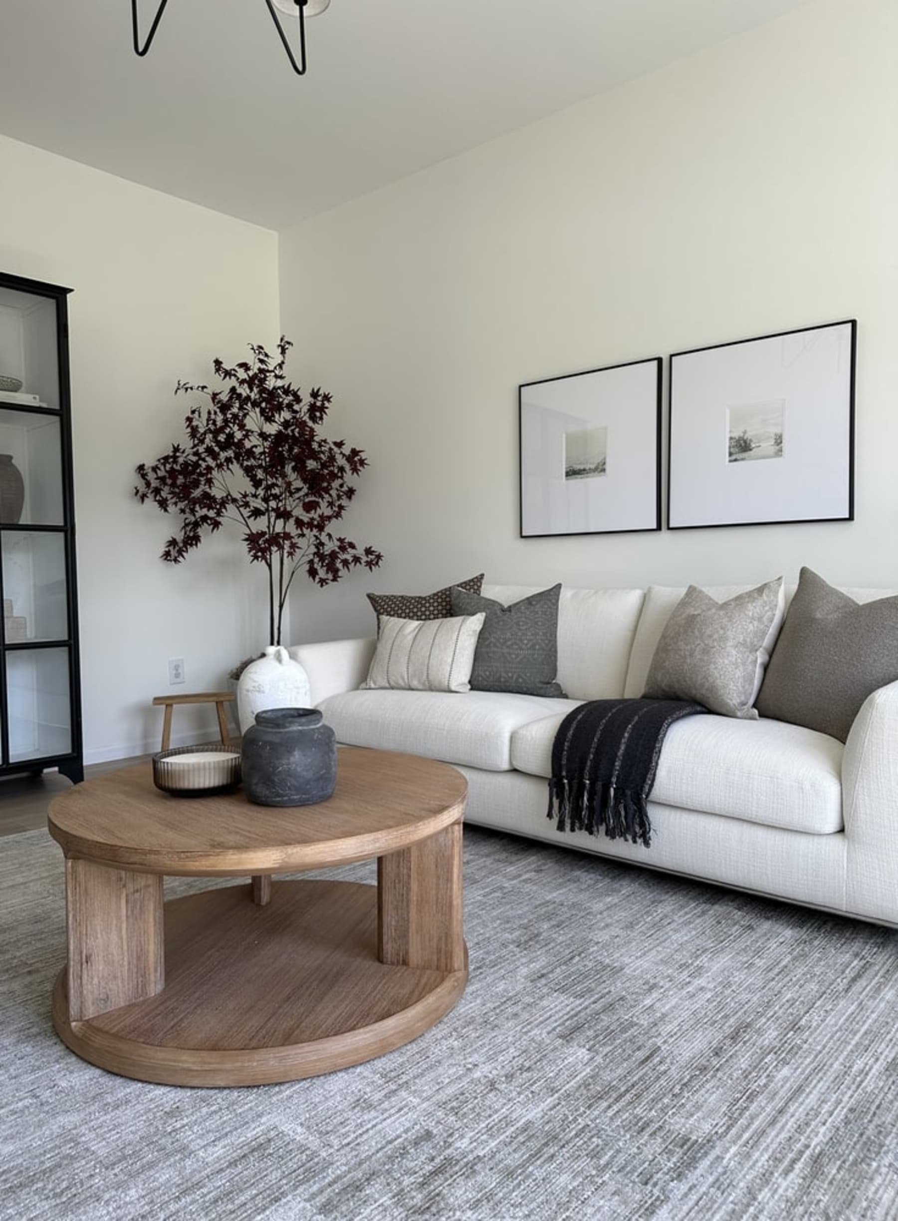 A white fabric sofa with a wooden round coffee table.