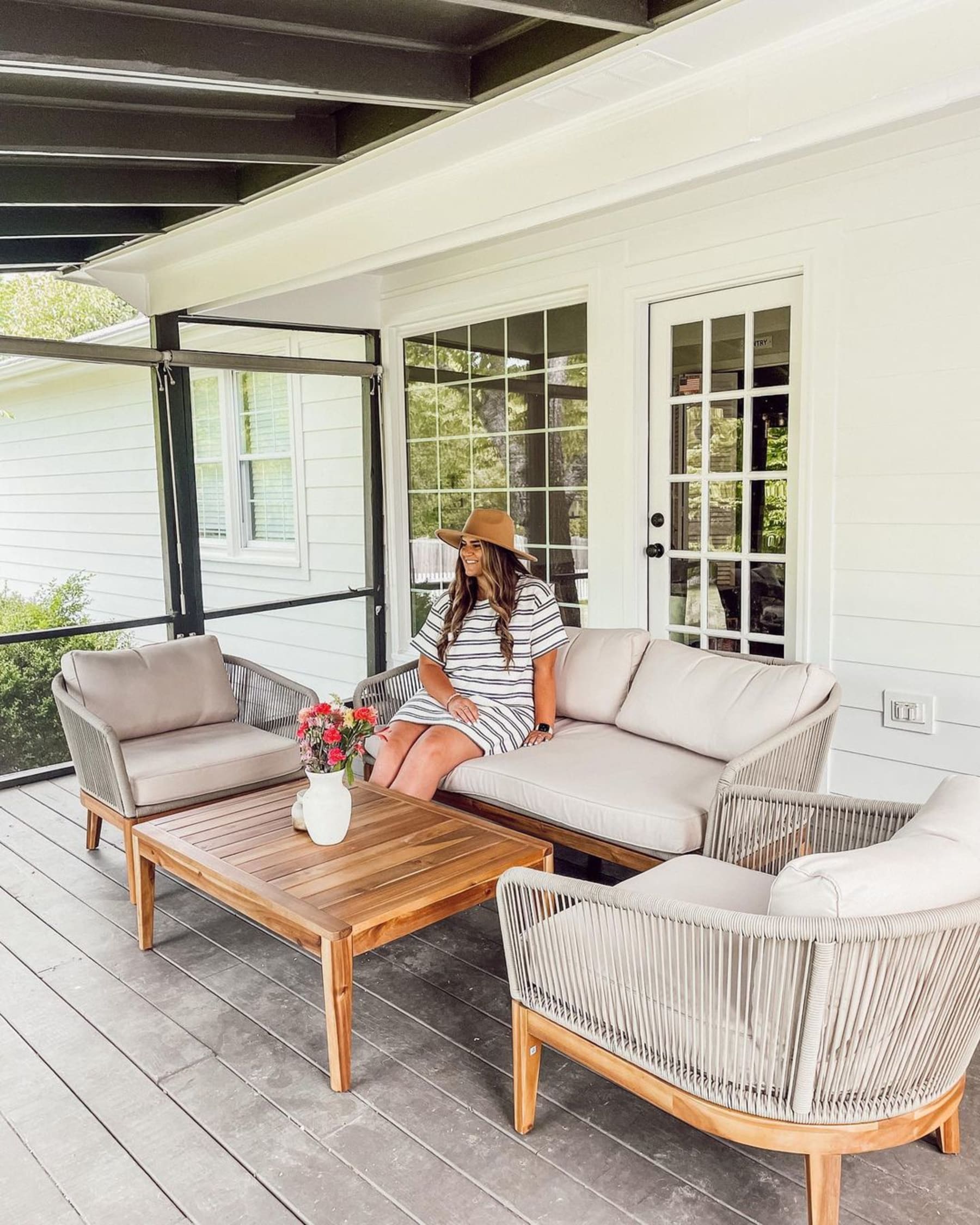 A person sitting on an outdoor sofa on their deck.