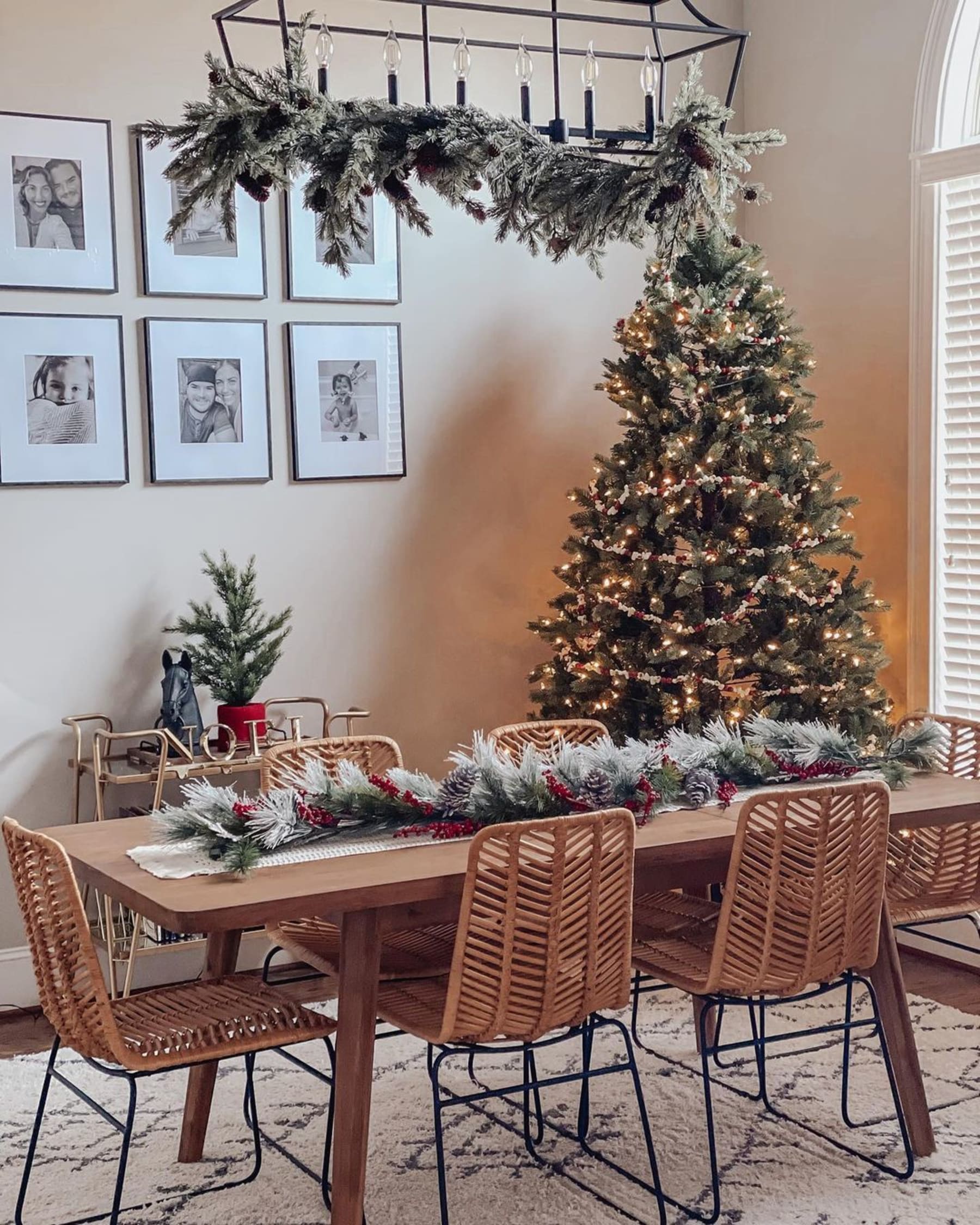 A wooden dining table with holly sprigs placed in the center of the table.