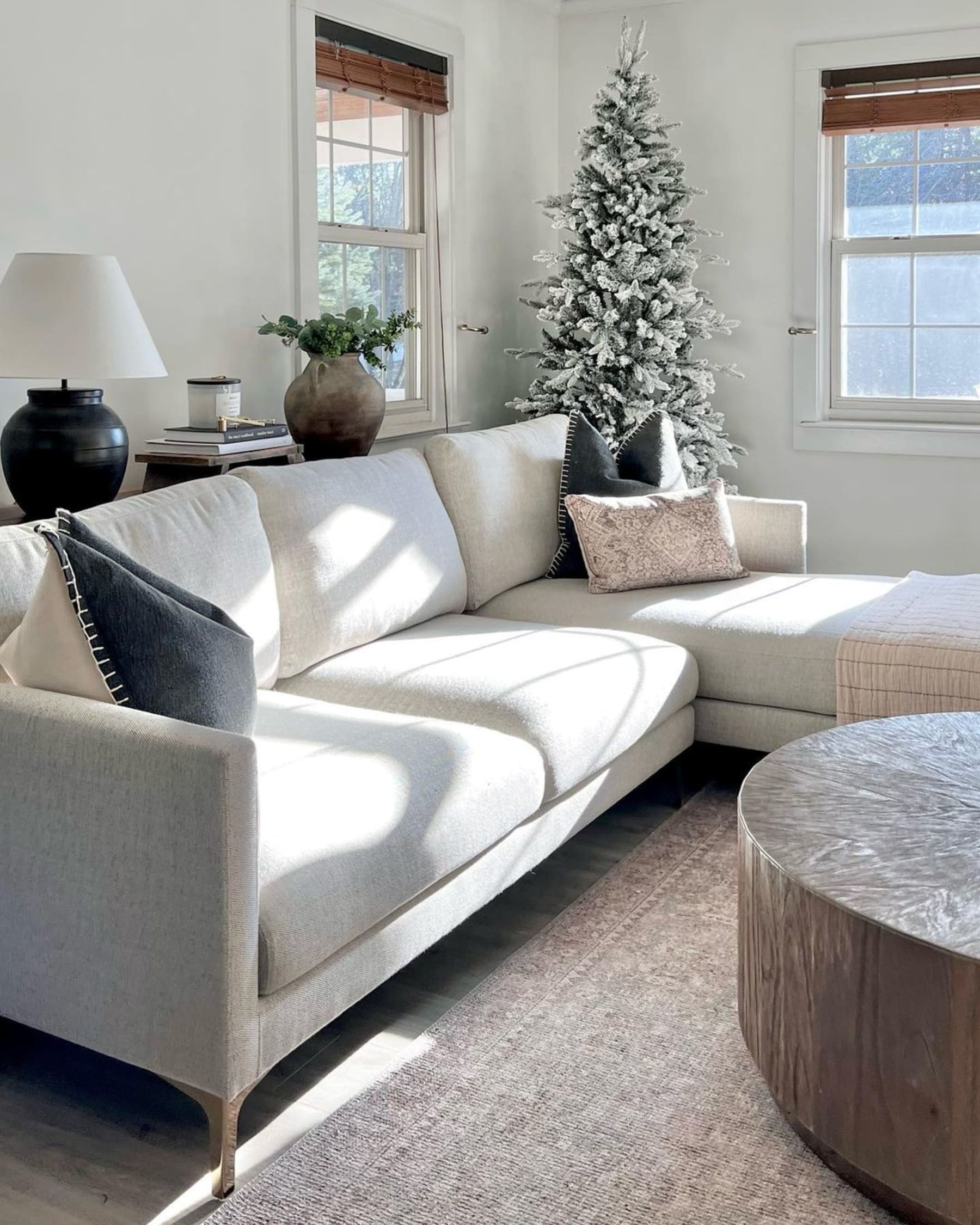 A white chaise sectional sofa with a Christmas tree behind it.