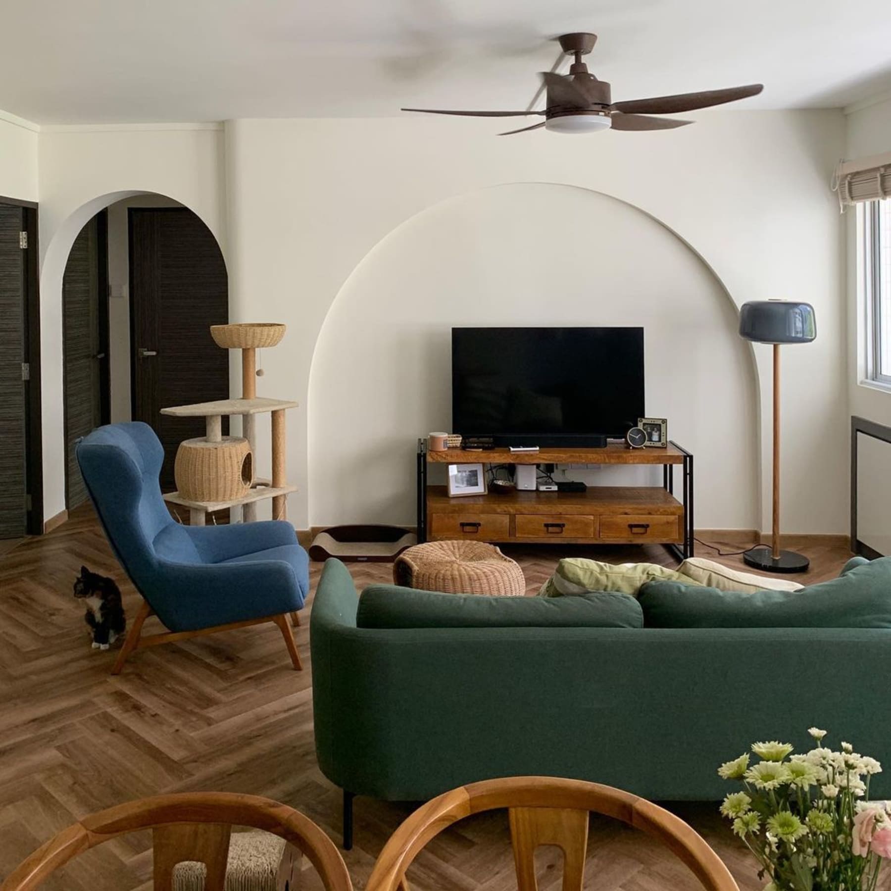 An uncluttered living room with a sofa, armchair, TV stand, and cat tower.