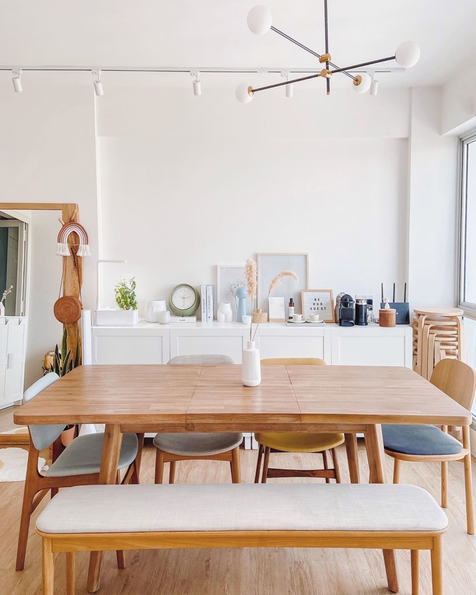 A white sideboard decorated with books, vases, and frames in the dining area.