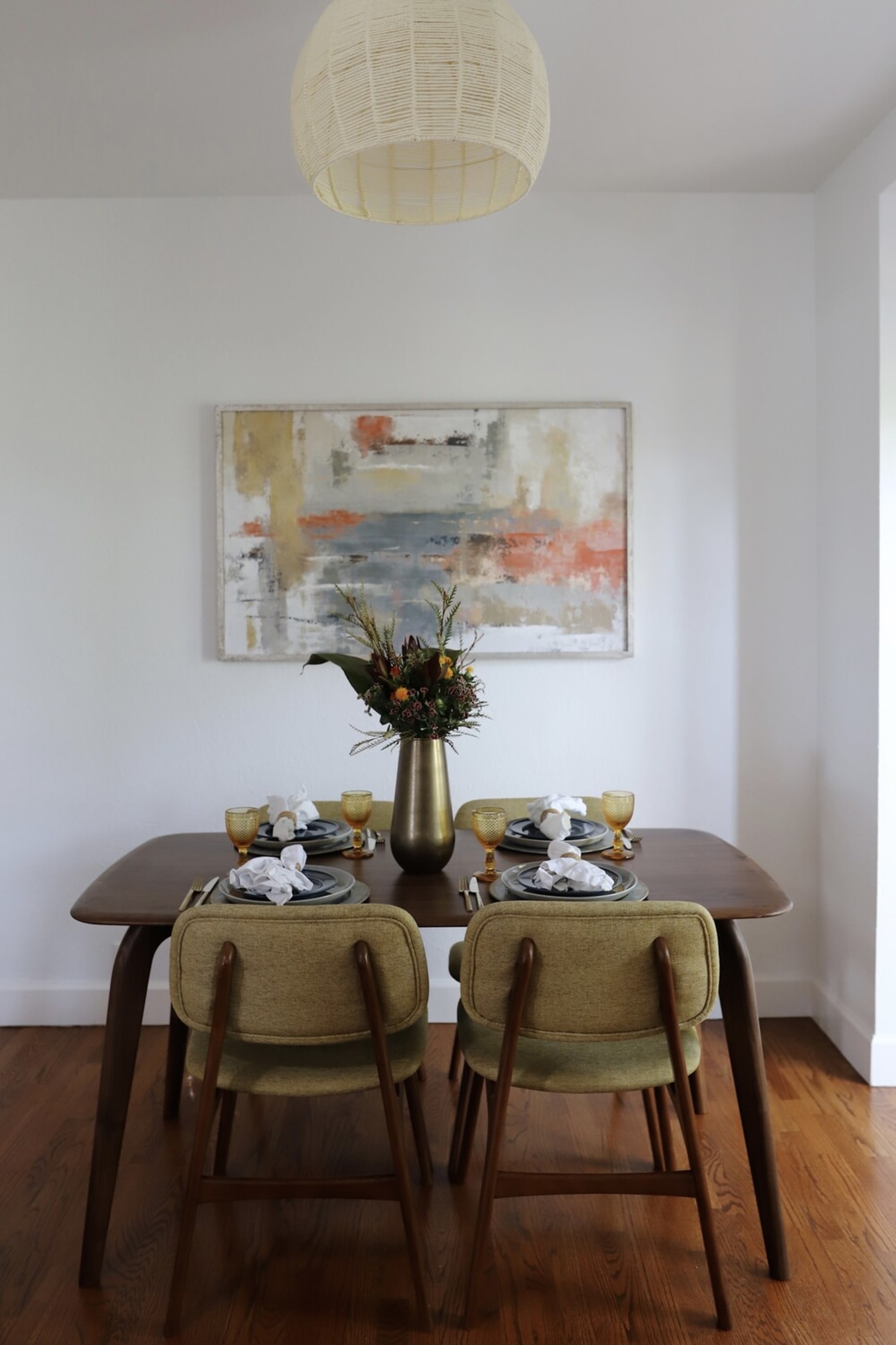 A walnut dining table set and a large vibrant painting.