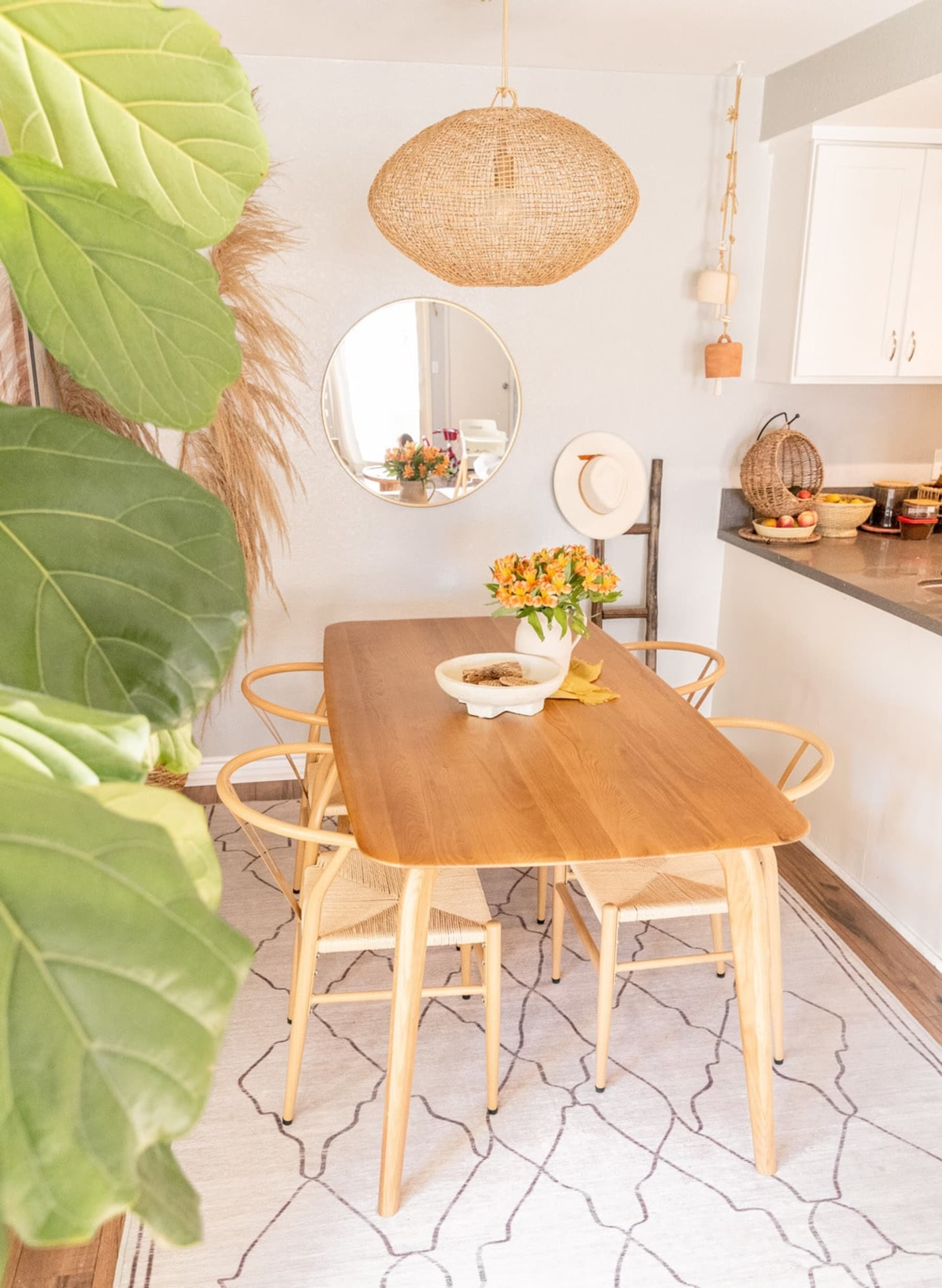 An oak wood dining table with a mirror hung up on the wall.