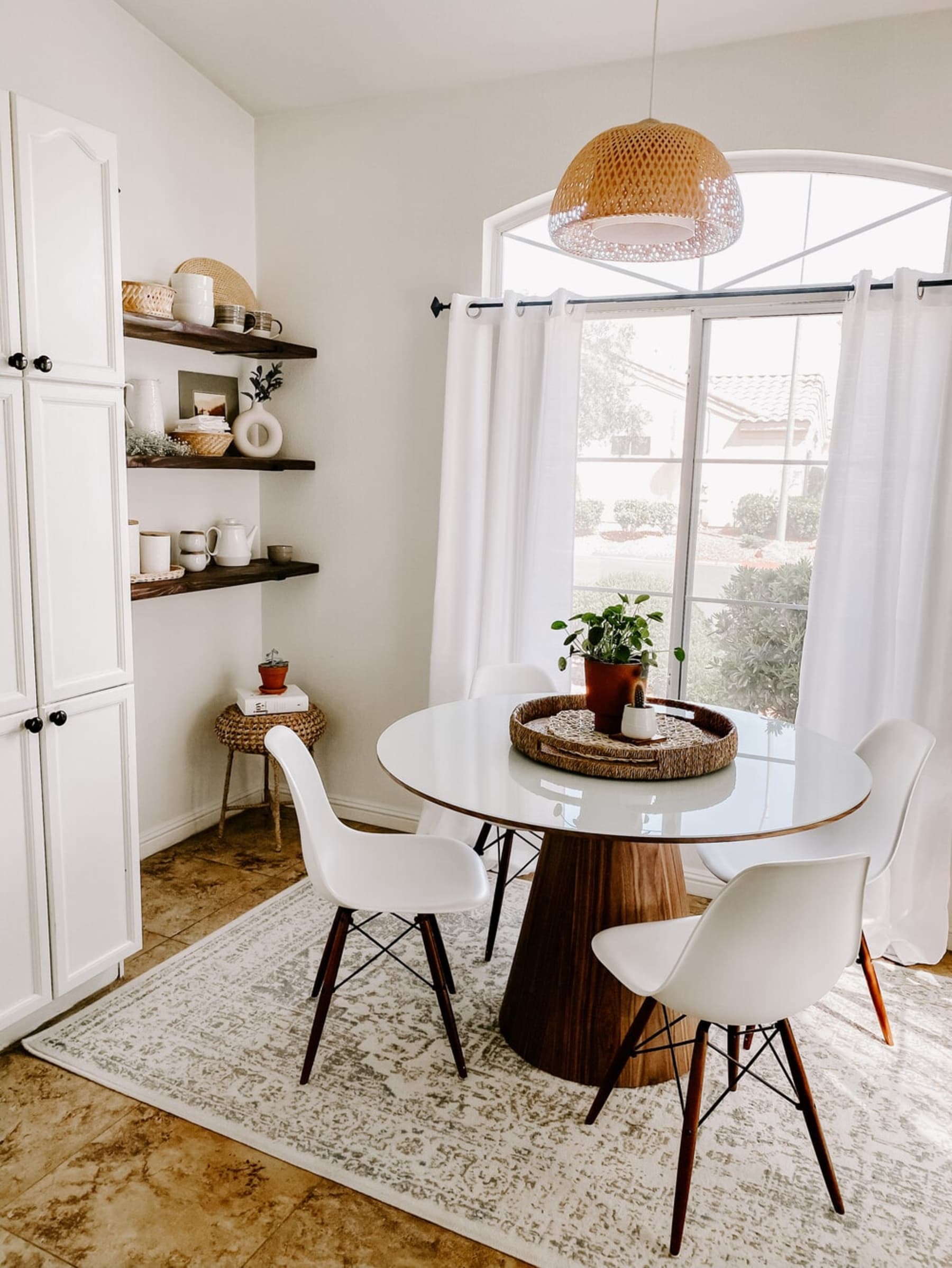 A round dining table with four chairs and three floating shelves in the dining room.