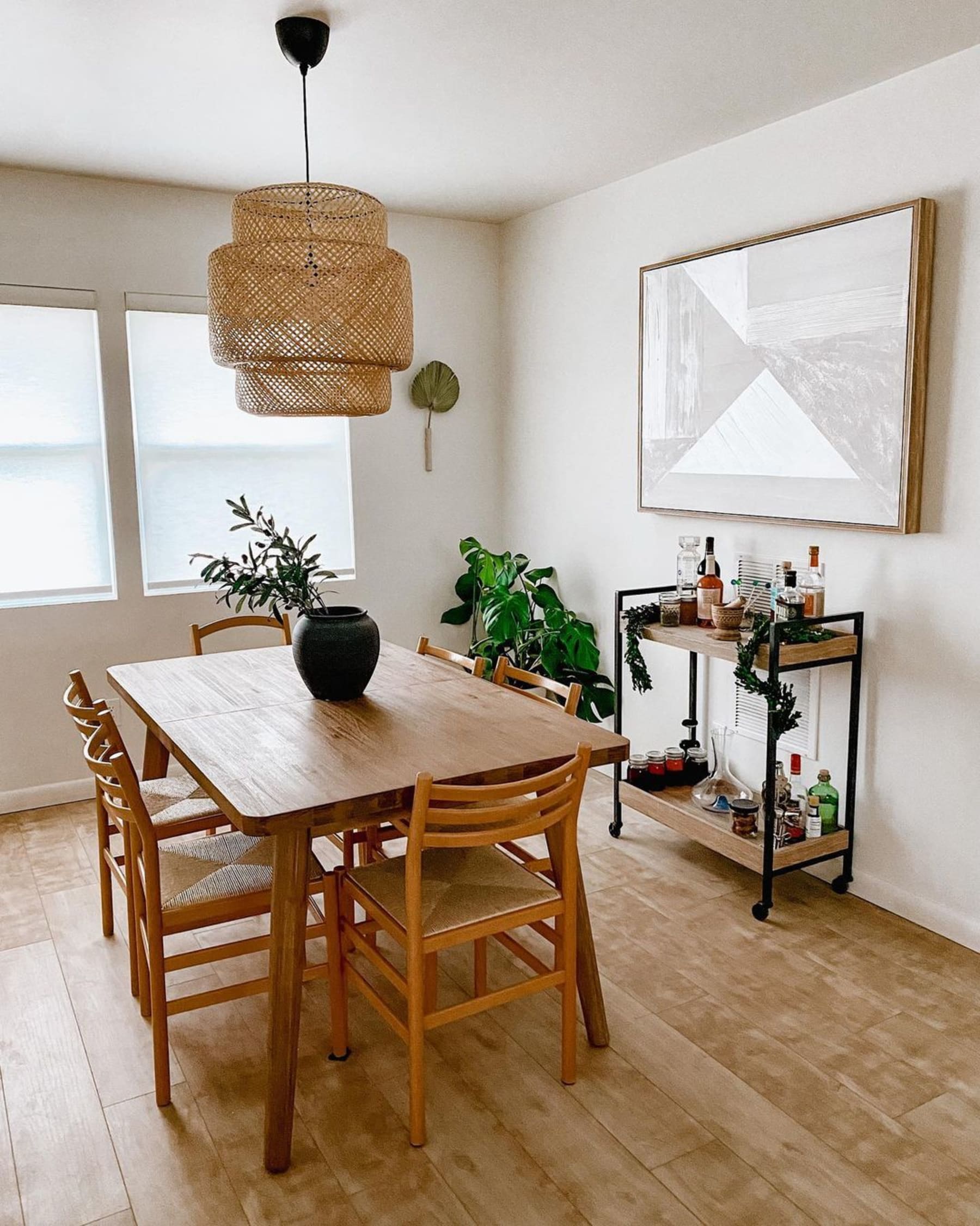 A wooden extendable dining table centered below a hanging lamp with a cane lampshade