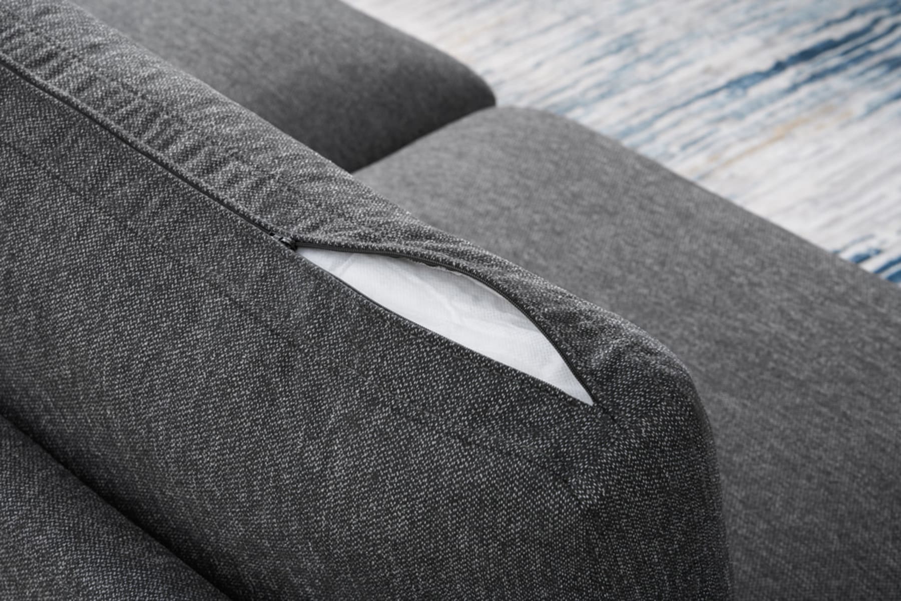 A black sofa cushion unzipped to reveal the foam and pocket spring filling.