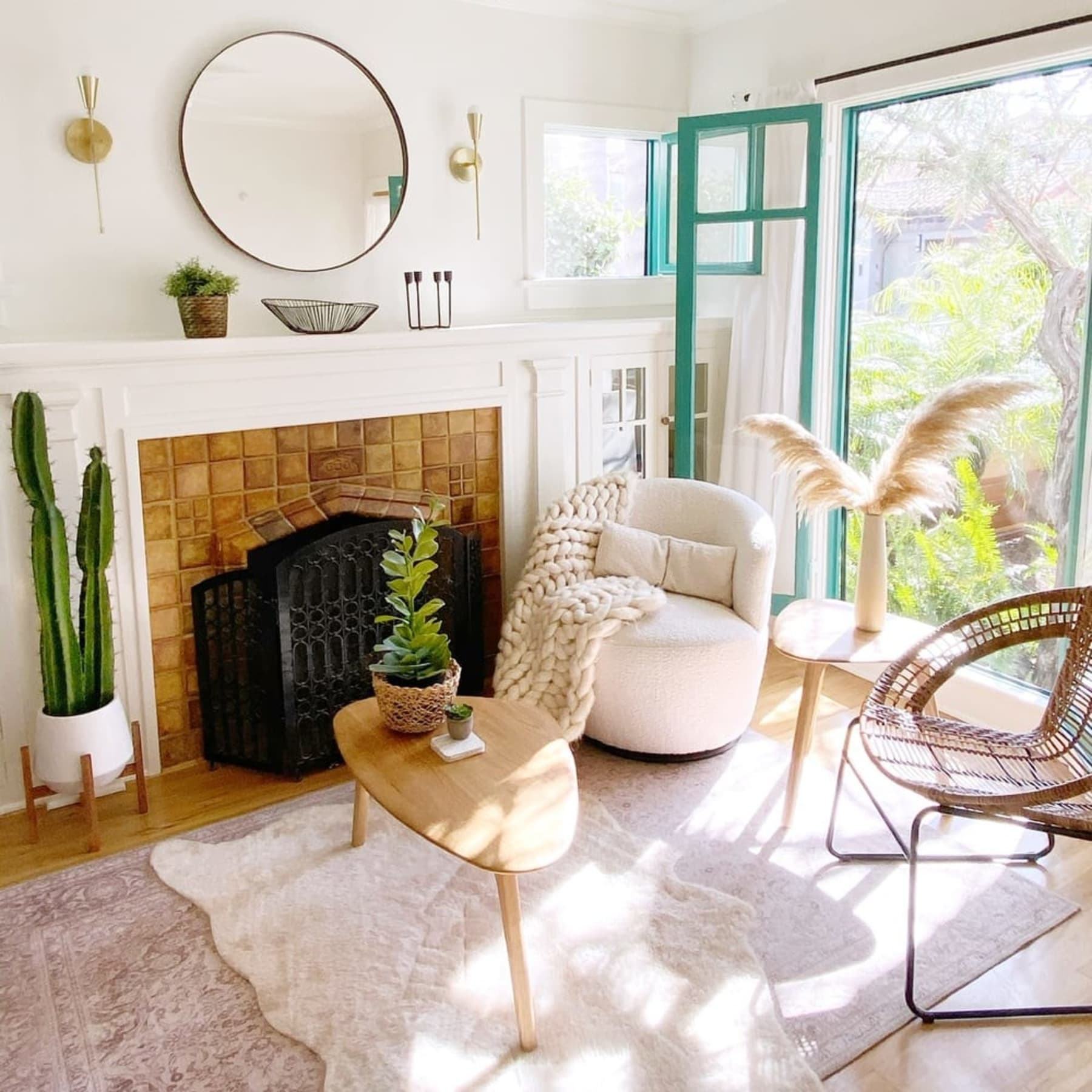 A swivel armchair, rattan armchair, and wooden tables beside a fireplace.