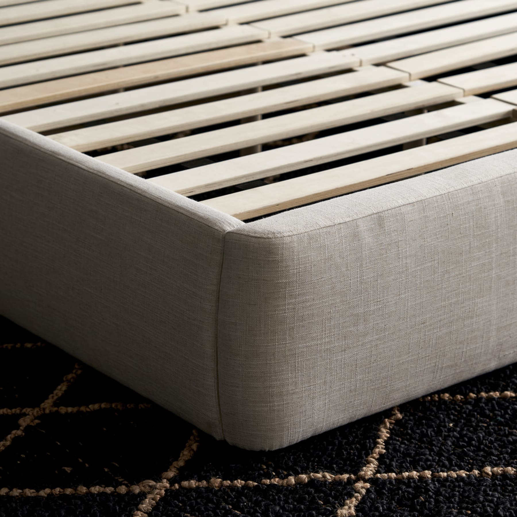 A close-up shot of the corner of a bed and the bed slats.