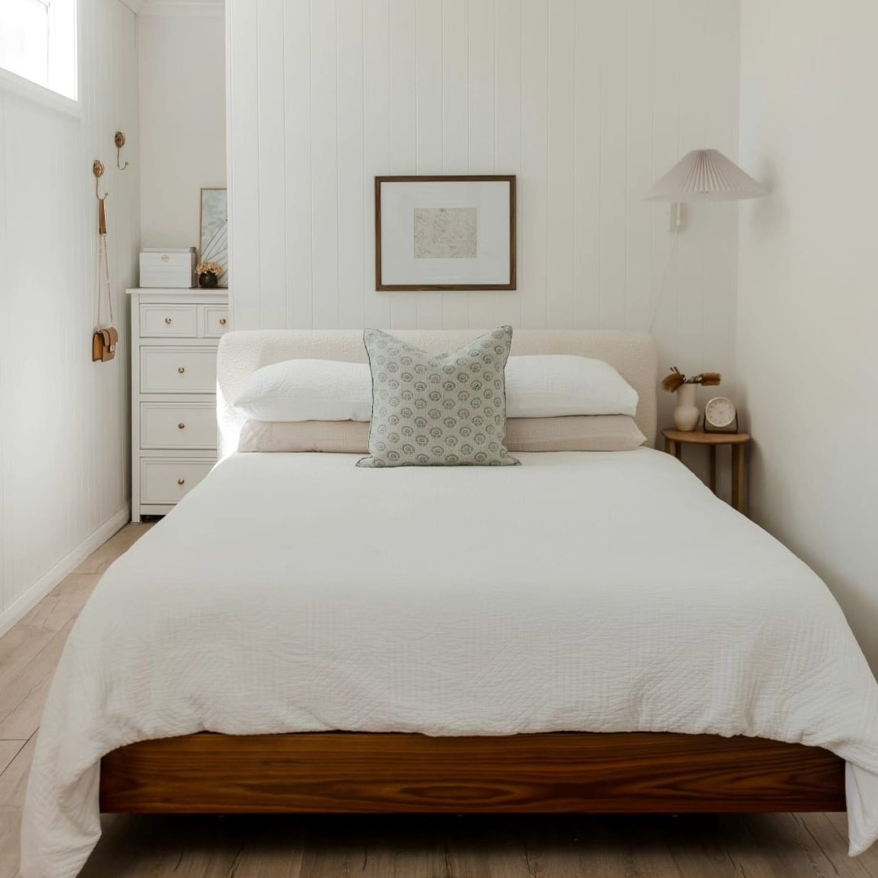 A bed with crisp white bedsheets in a small bedroom.