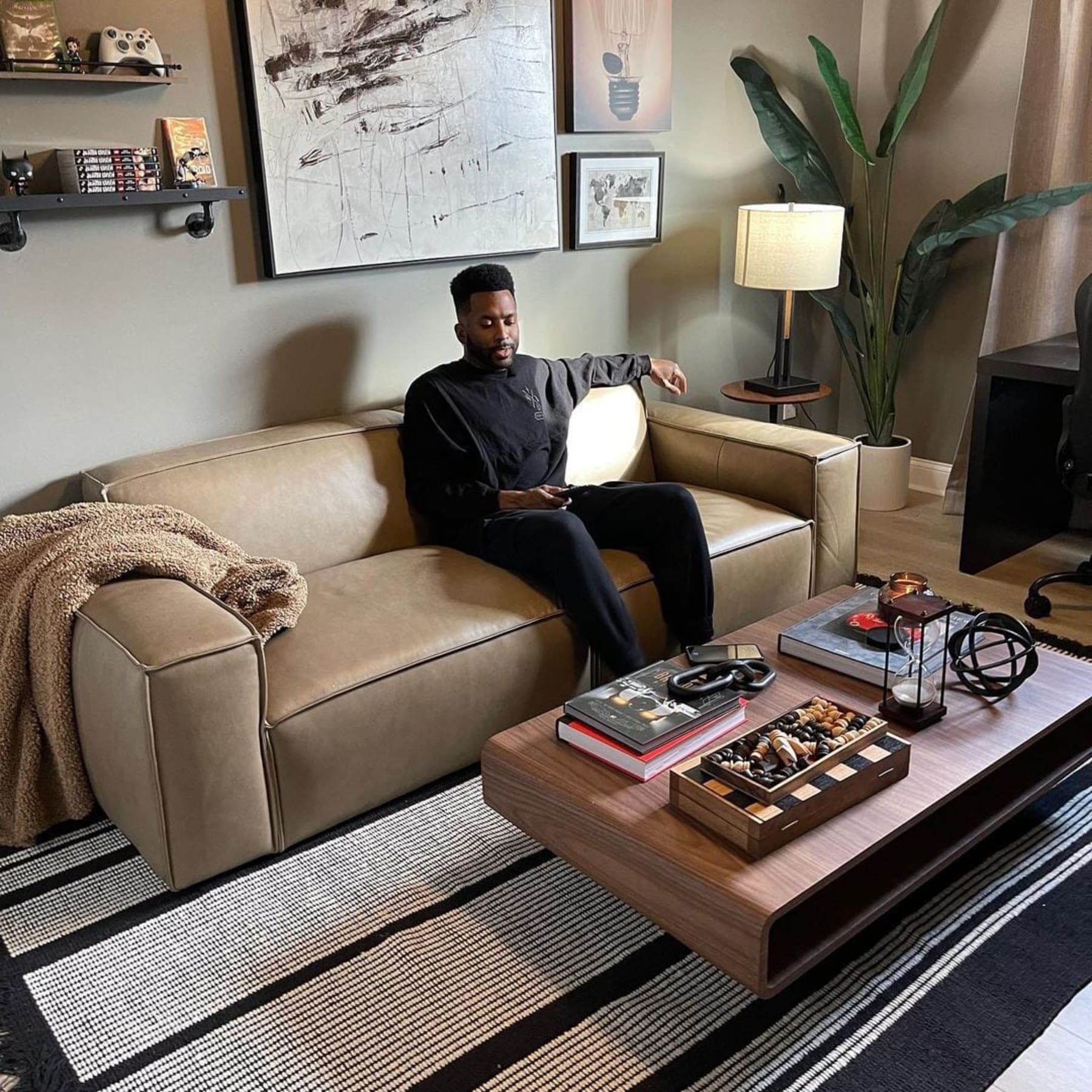 A person sitting on a 2-seater leather sofa in a living room.