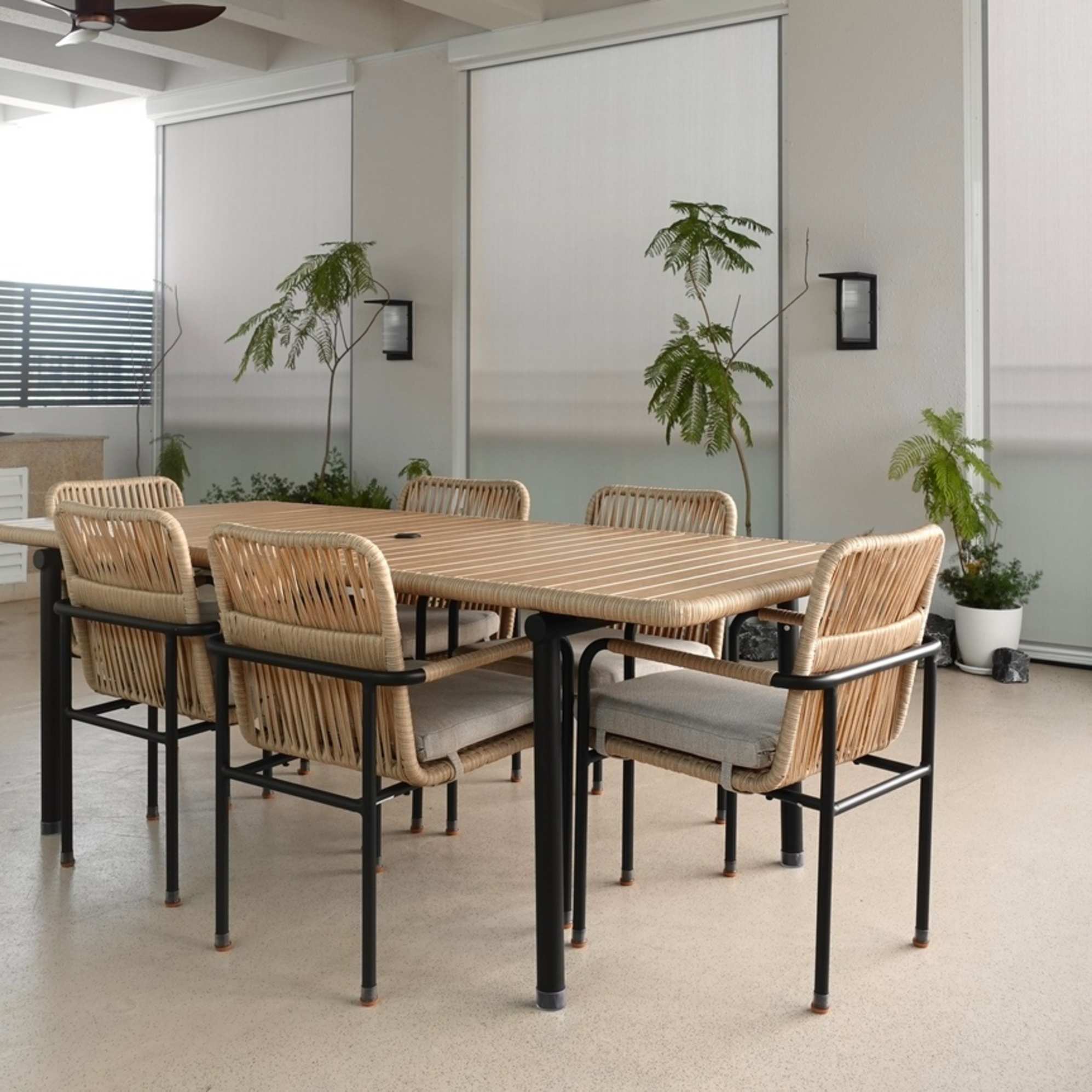 An outdoor dining table with 6 matching wicker dining chairs placed in an enclosed space.