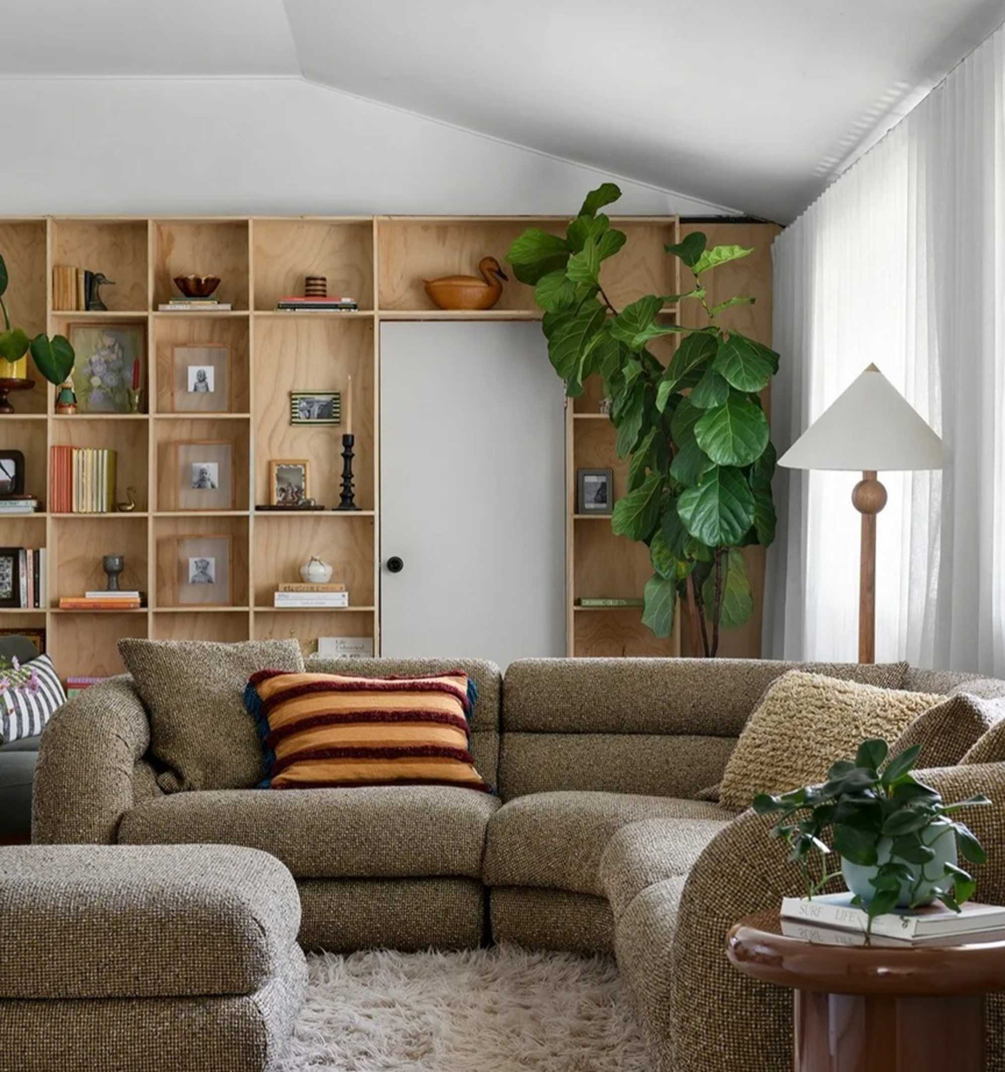 A moss green performance fabric l-shape sectional sofa placed in a living room with a built-in wooden shelf.