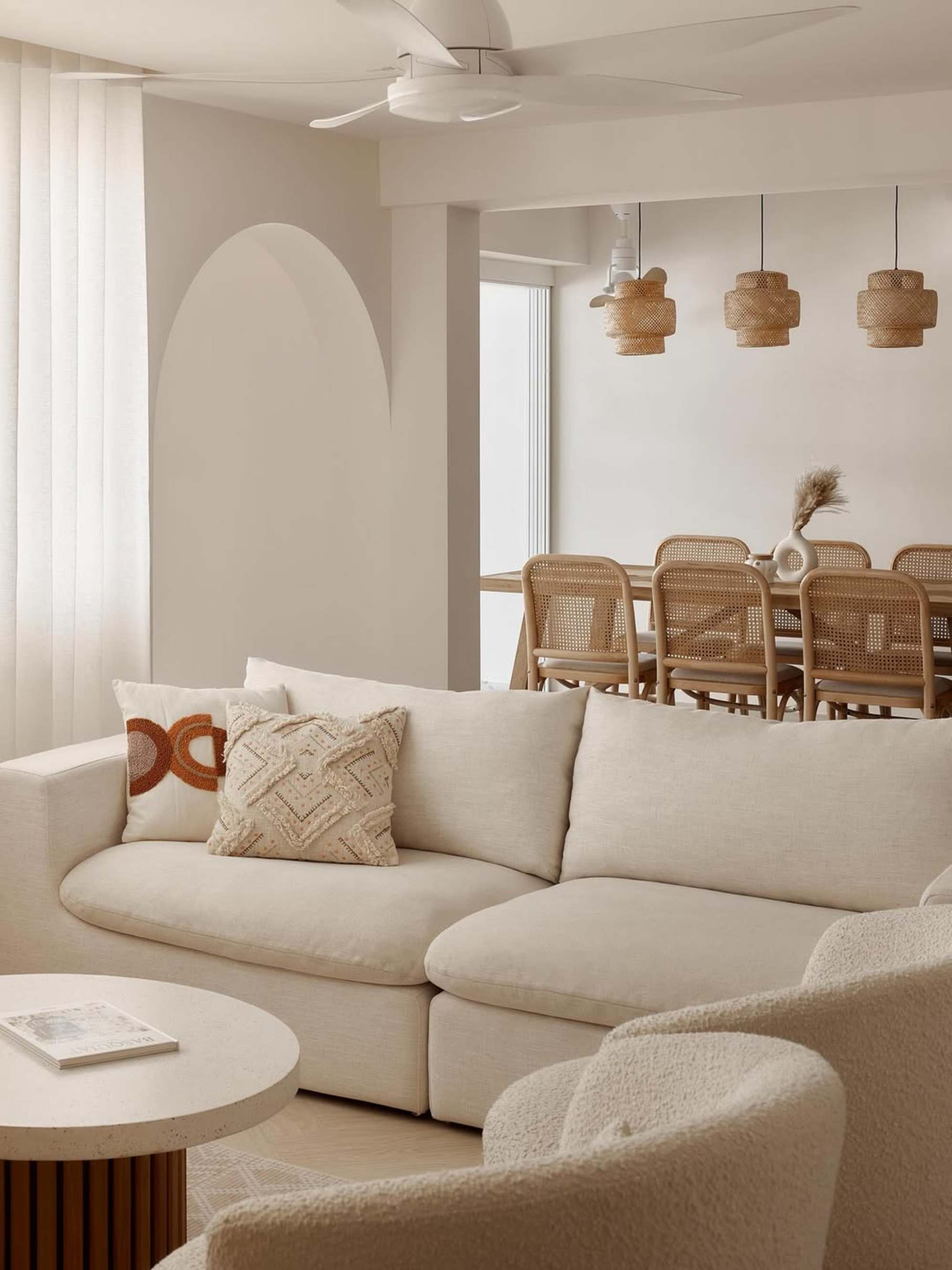 A white sofa placed in a living room with two throw cushions.