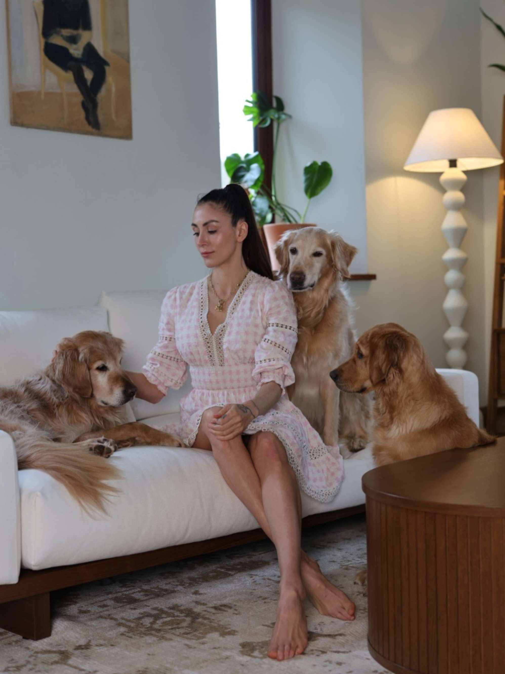 A woman sitting on a performance fabric sofa with three golden retrievers. 