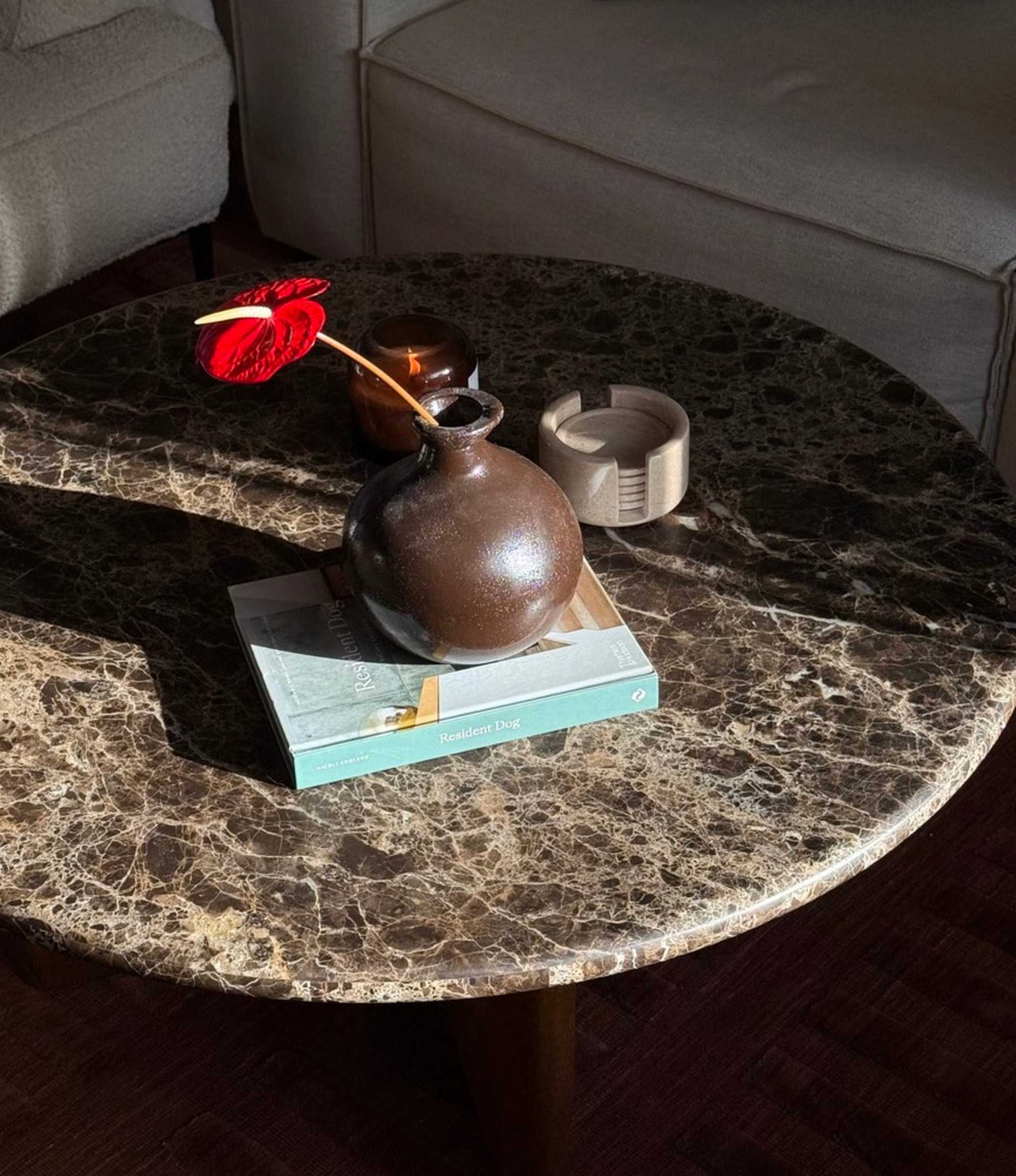 A damascus marble coffee table with a book, vase, and coasters placed on its surface.