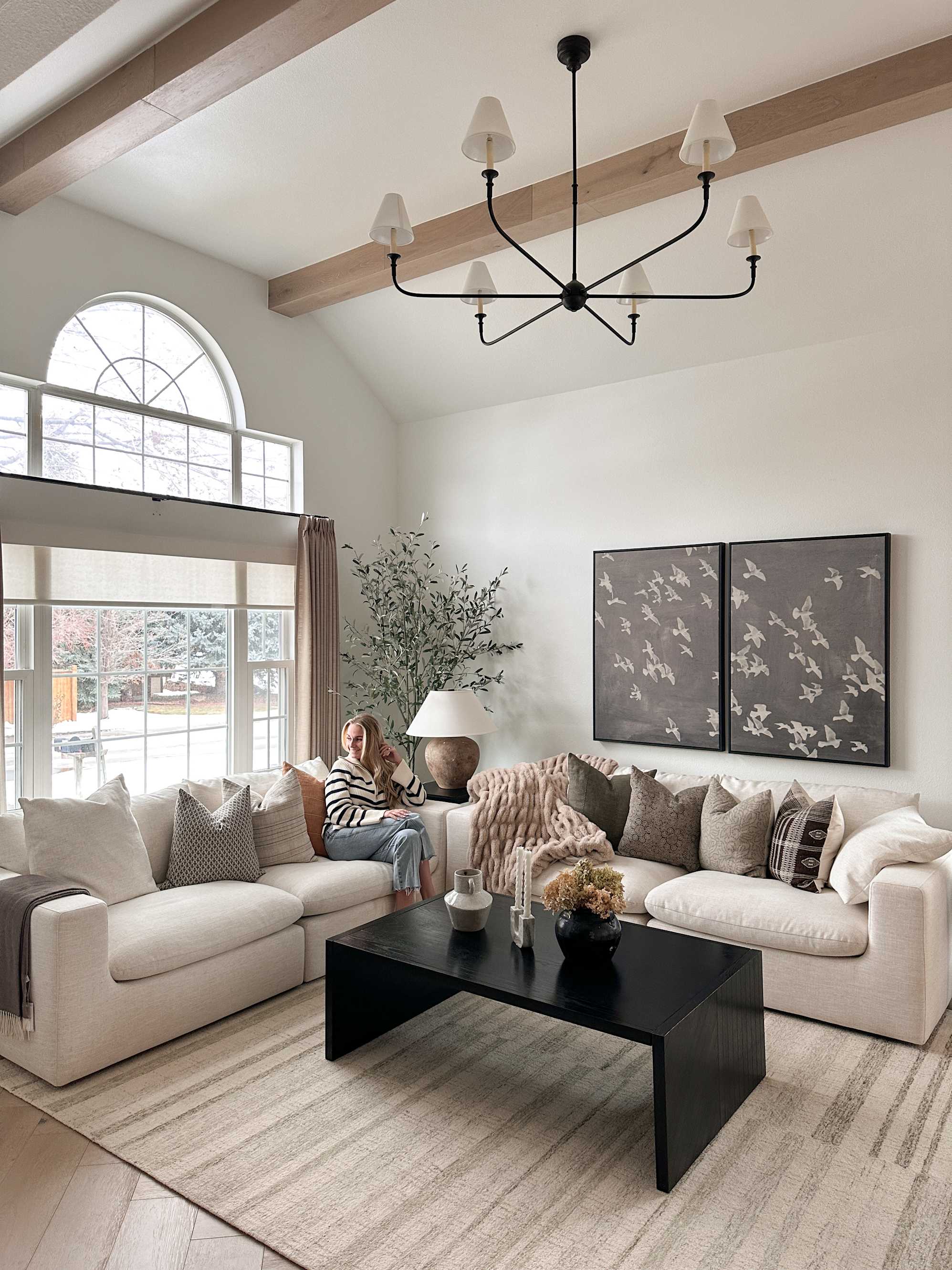 A lady sitting on her white sofa in her living room.