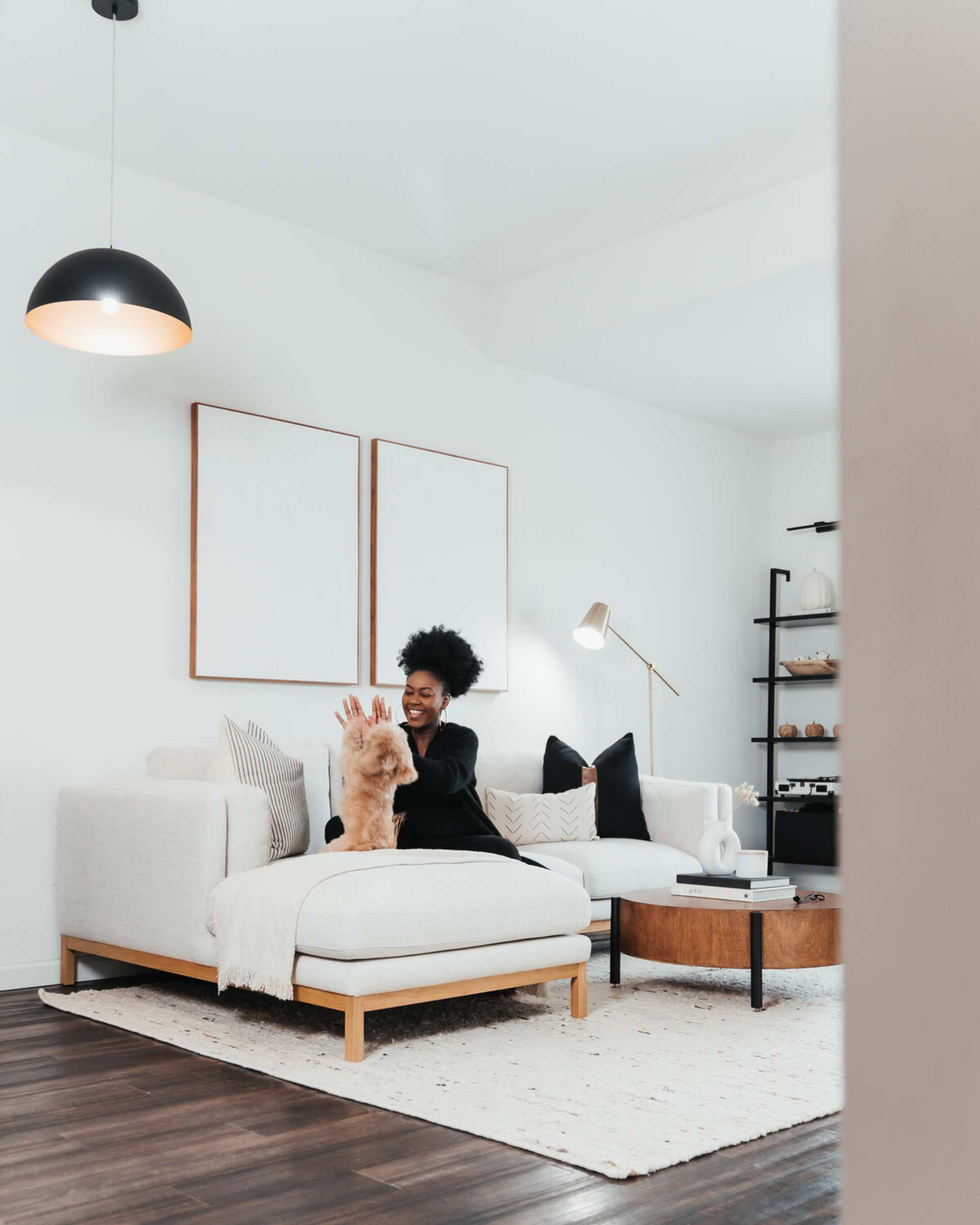 A person sitting on a sectional sofa playing with their dog.