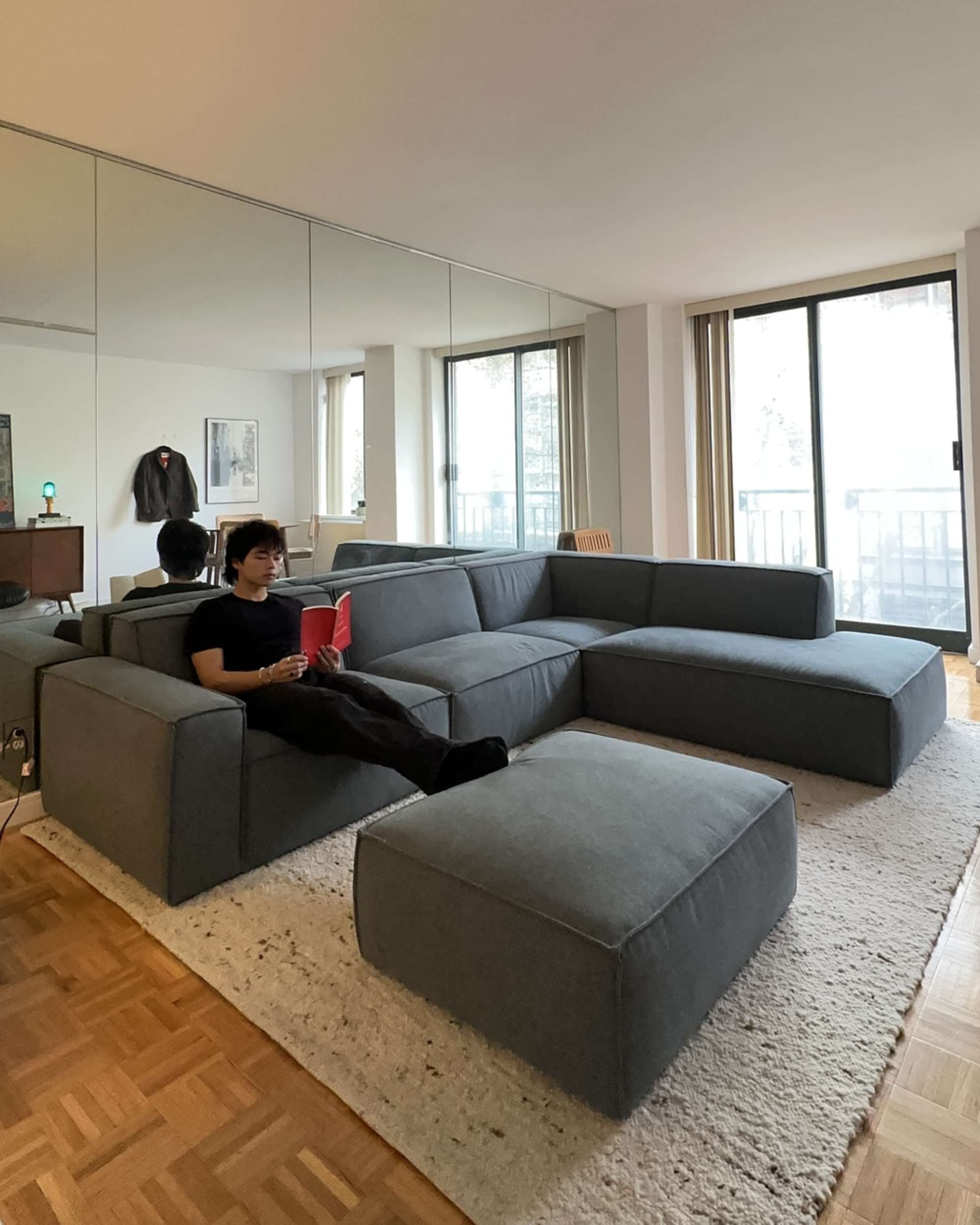 A person lounging on a blue sofa with a book.