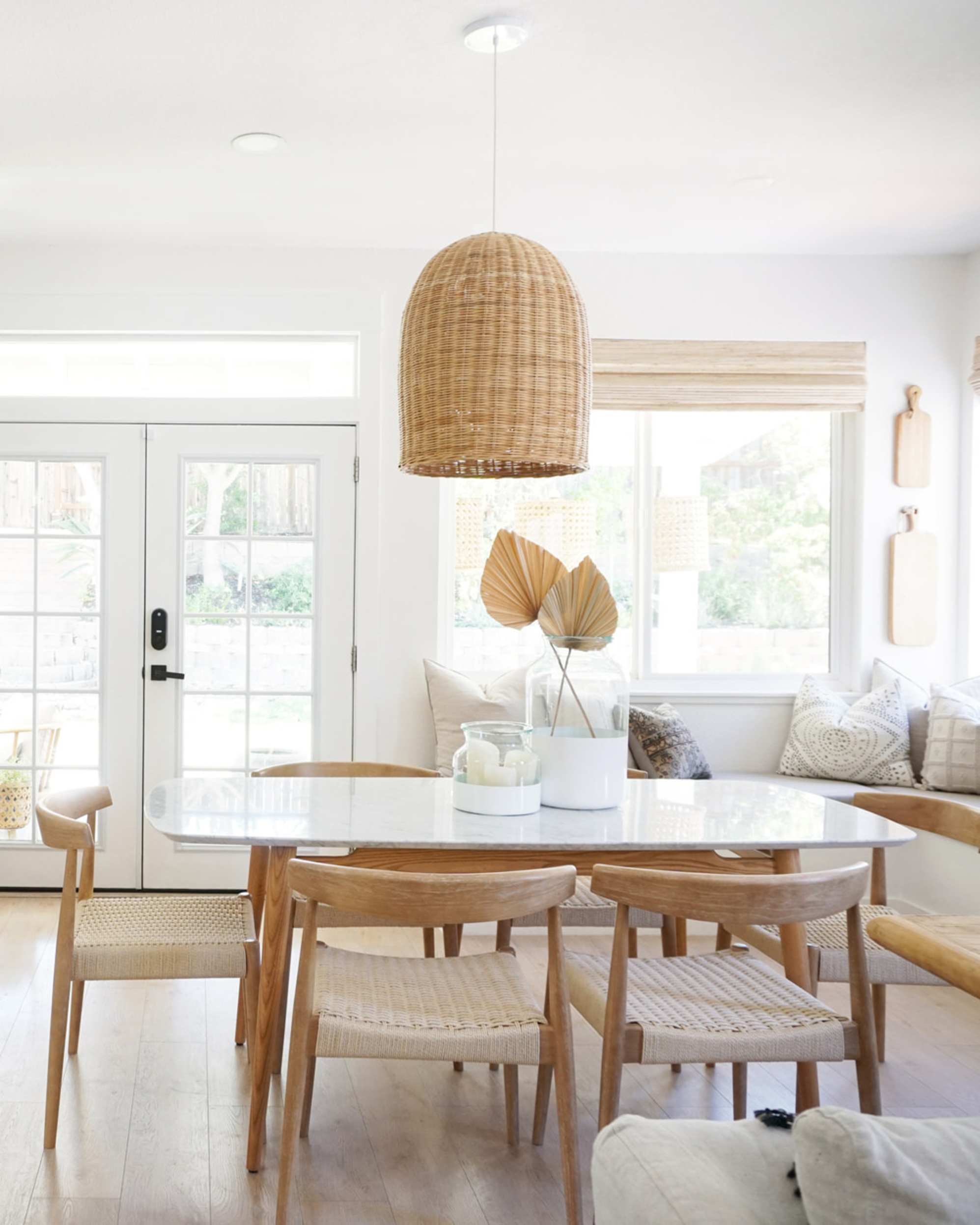 A marble dining table and complementing dining chairs with a woven seat.
