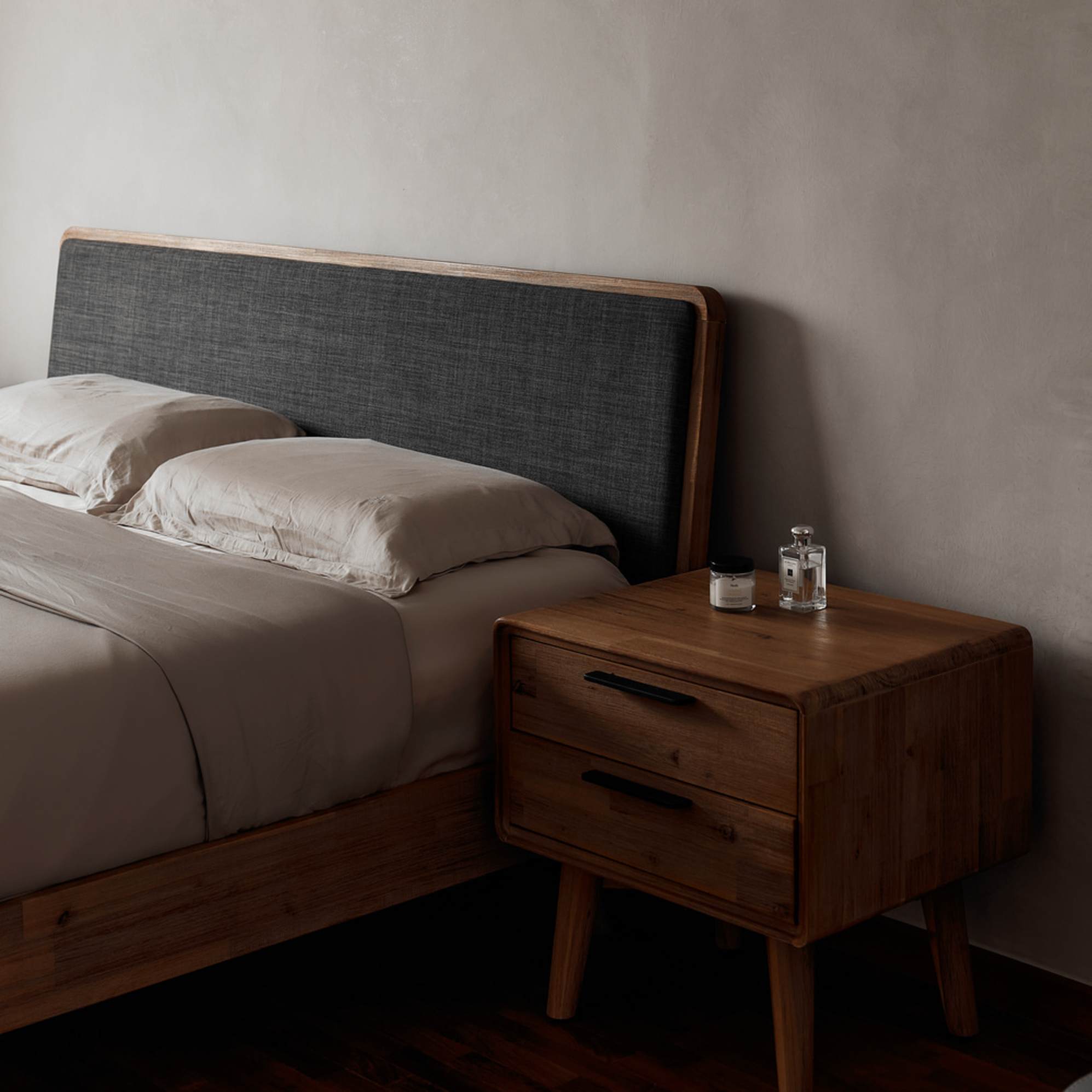 An acacia wood with a fabric headboard and a matching bedside table.