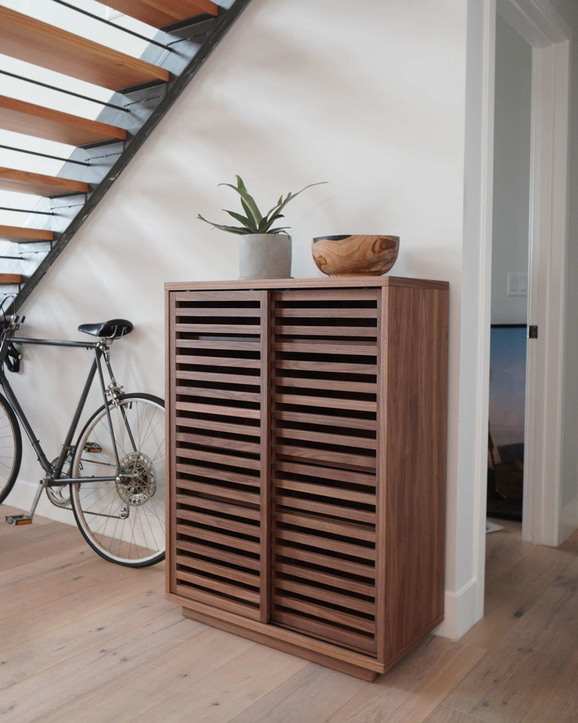 A walnut wood cabinet placed under a staircase.