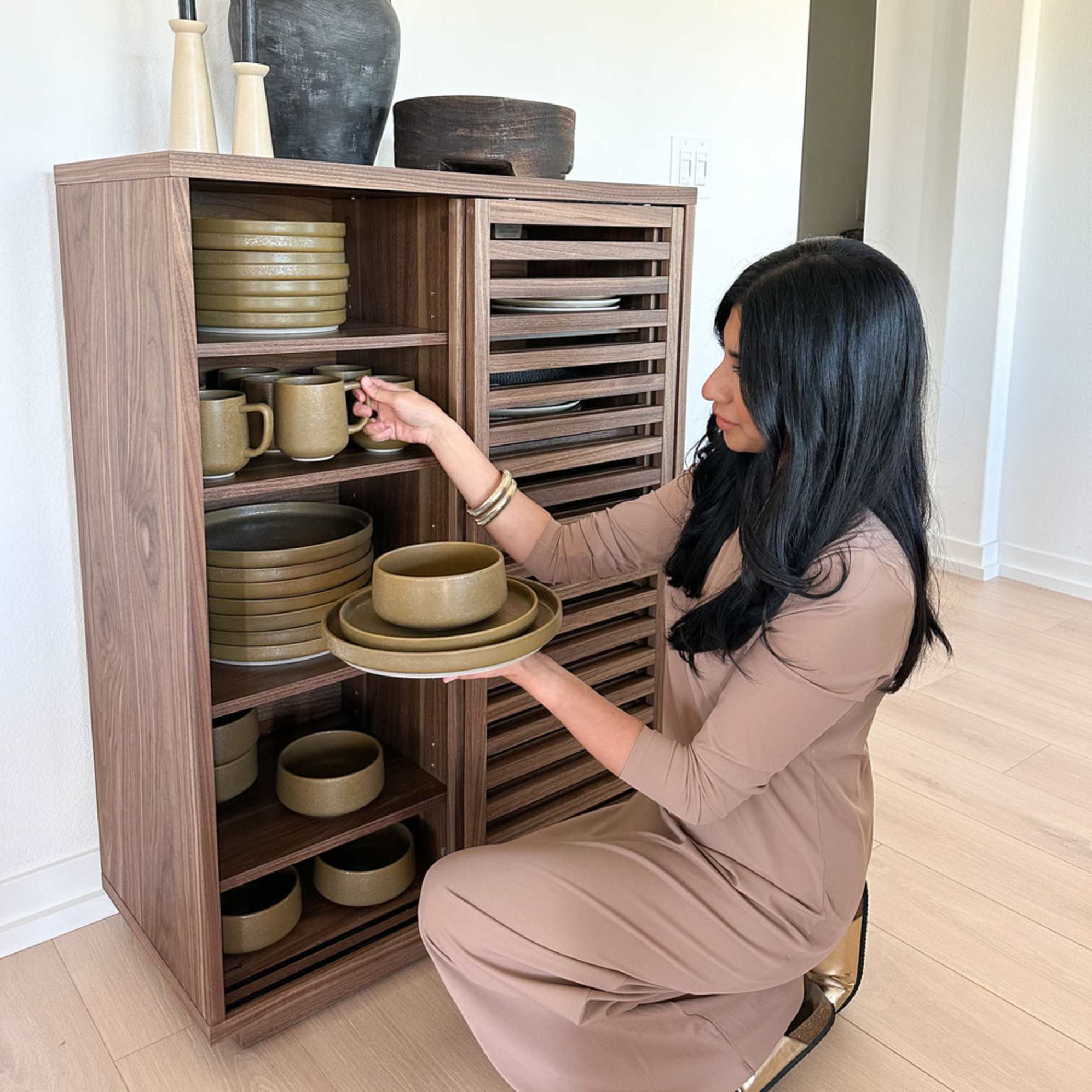 A person taking out tableware and mugs from a cabinet.