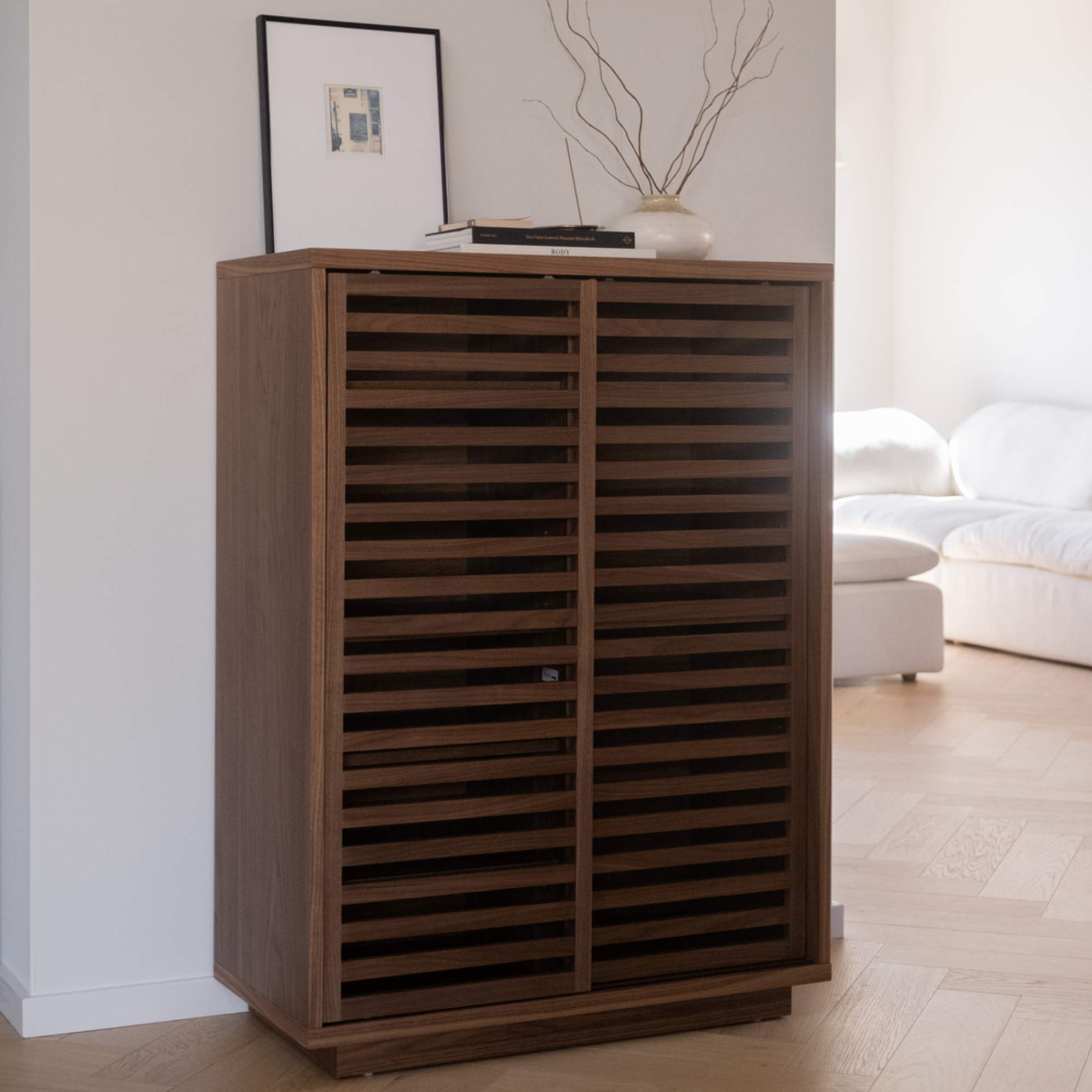 A walnut wood cabinet with artwork and decor placed atop.