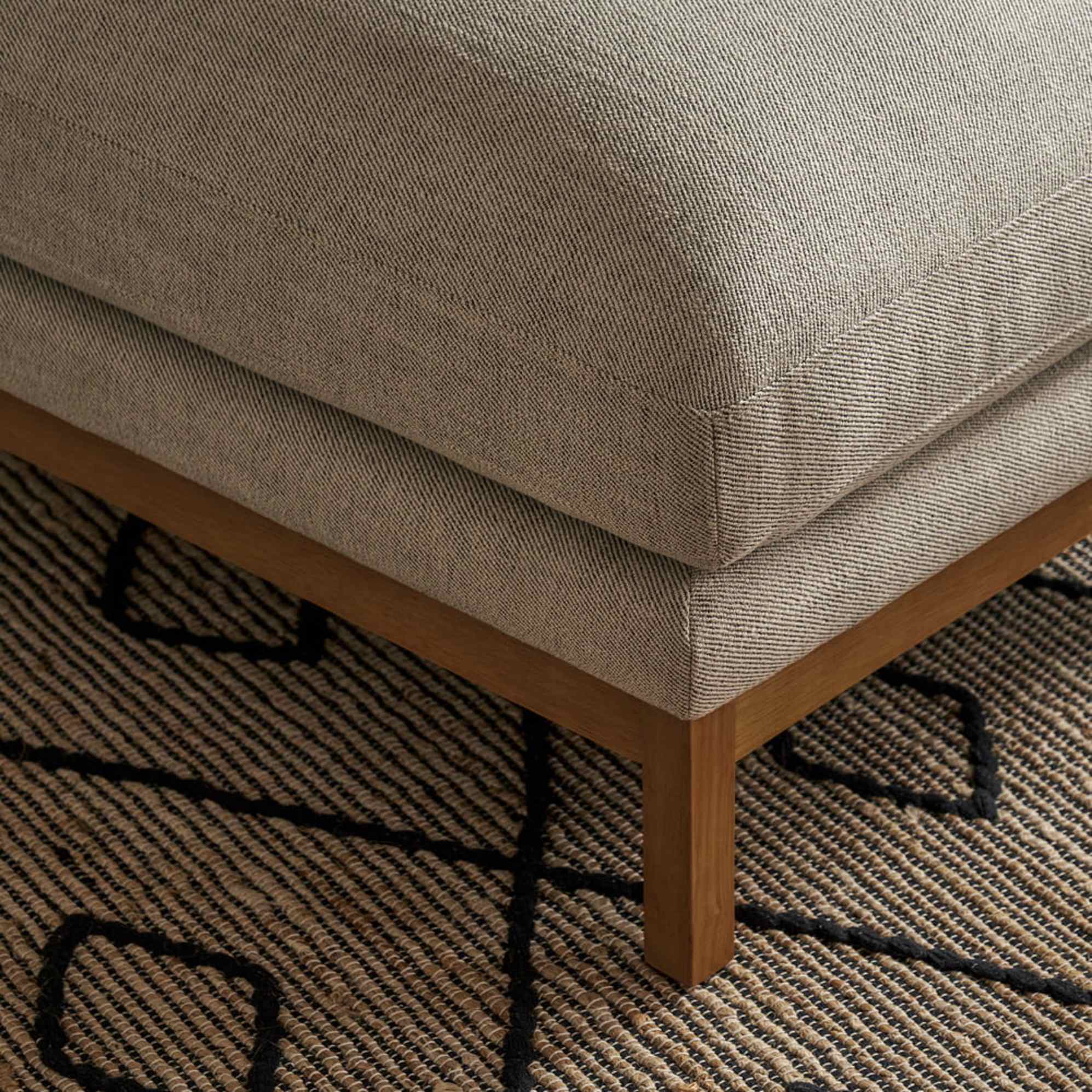 A close-up of the wooden legs of a chaise sectional sofa.