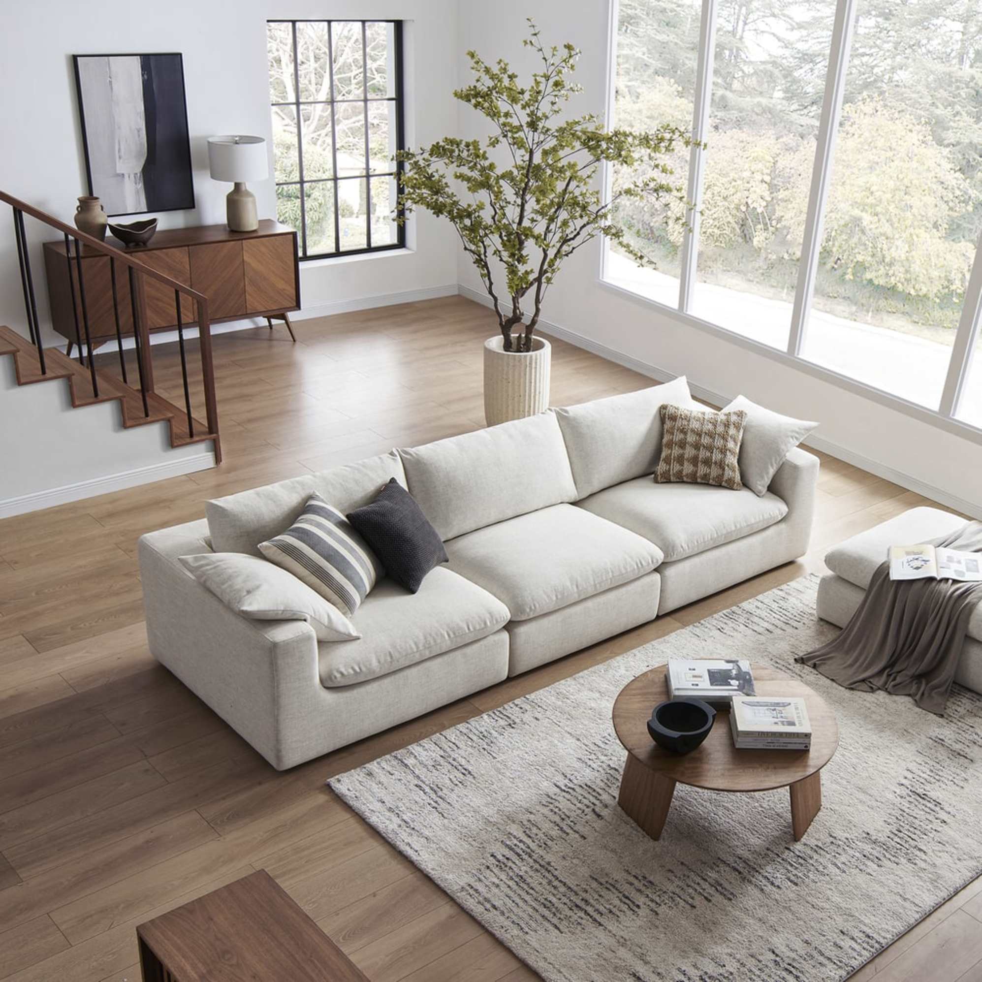 An extended sofa placed in a living room with a matching ottoman.