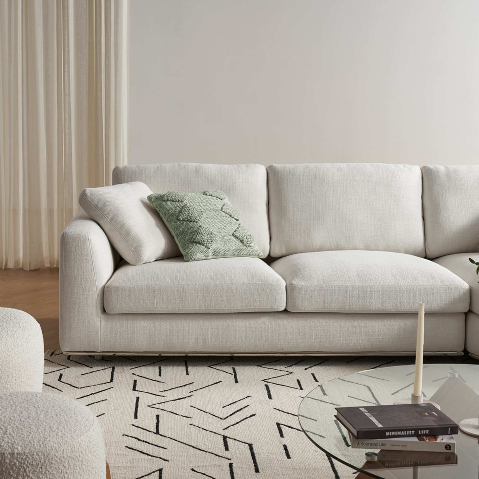 A white chaise sectional sofa with a geometric-patterned area rug placed beneath.