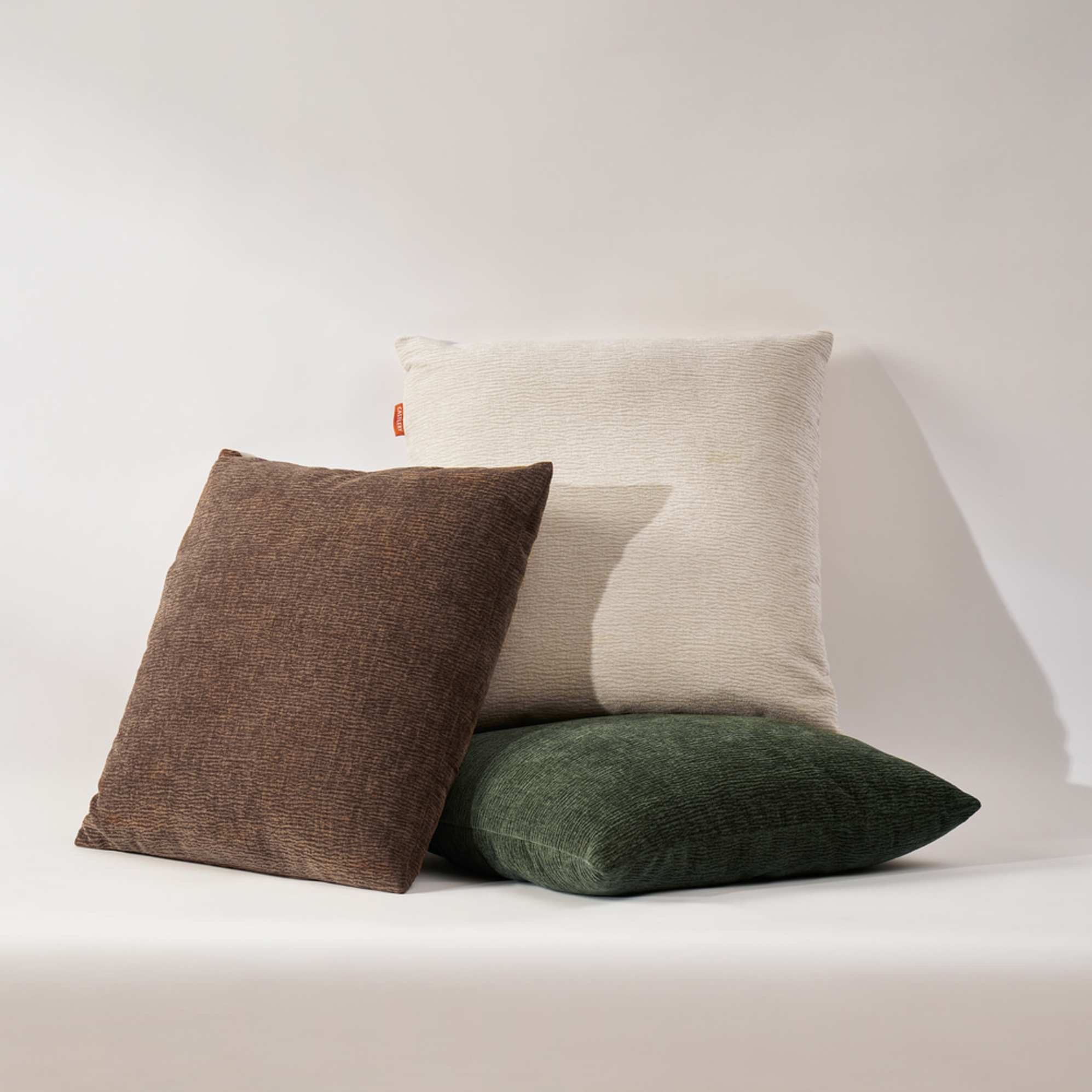 Three cushions in different colors stacked up against each other.