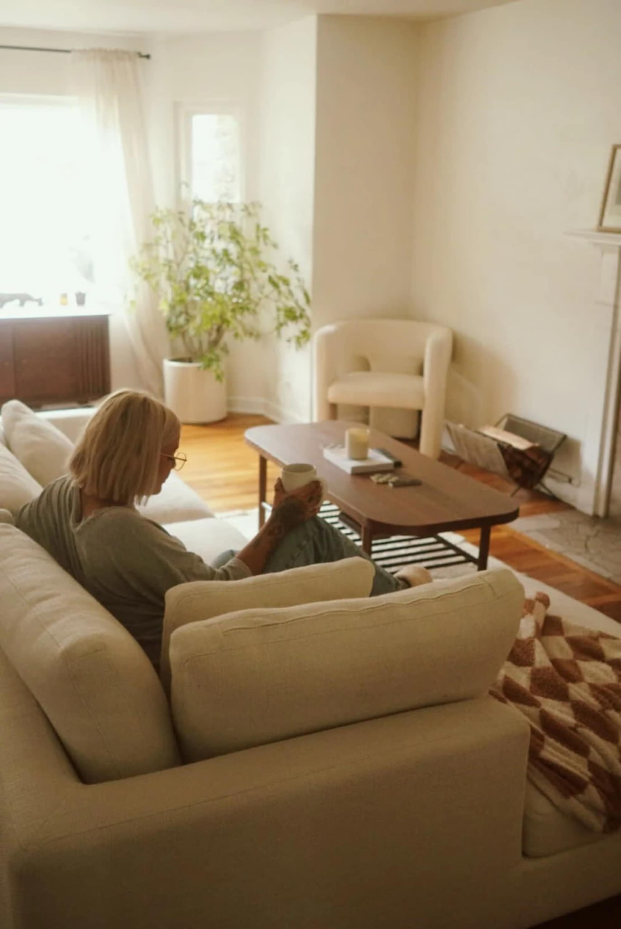 Woman enjoying coffee on her white sectional sofa in her living room