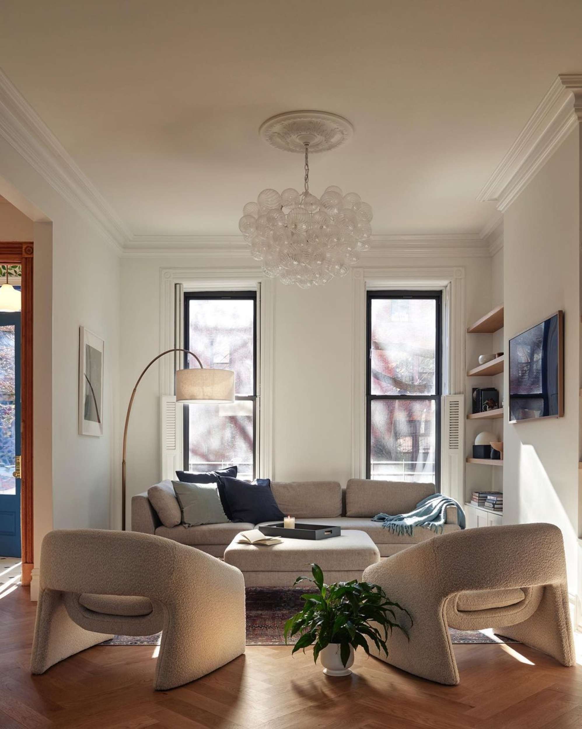 A sofa placed against the wall with two floor-to-ceiling windows.