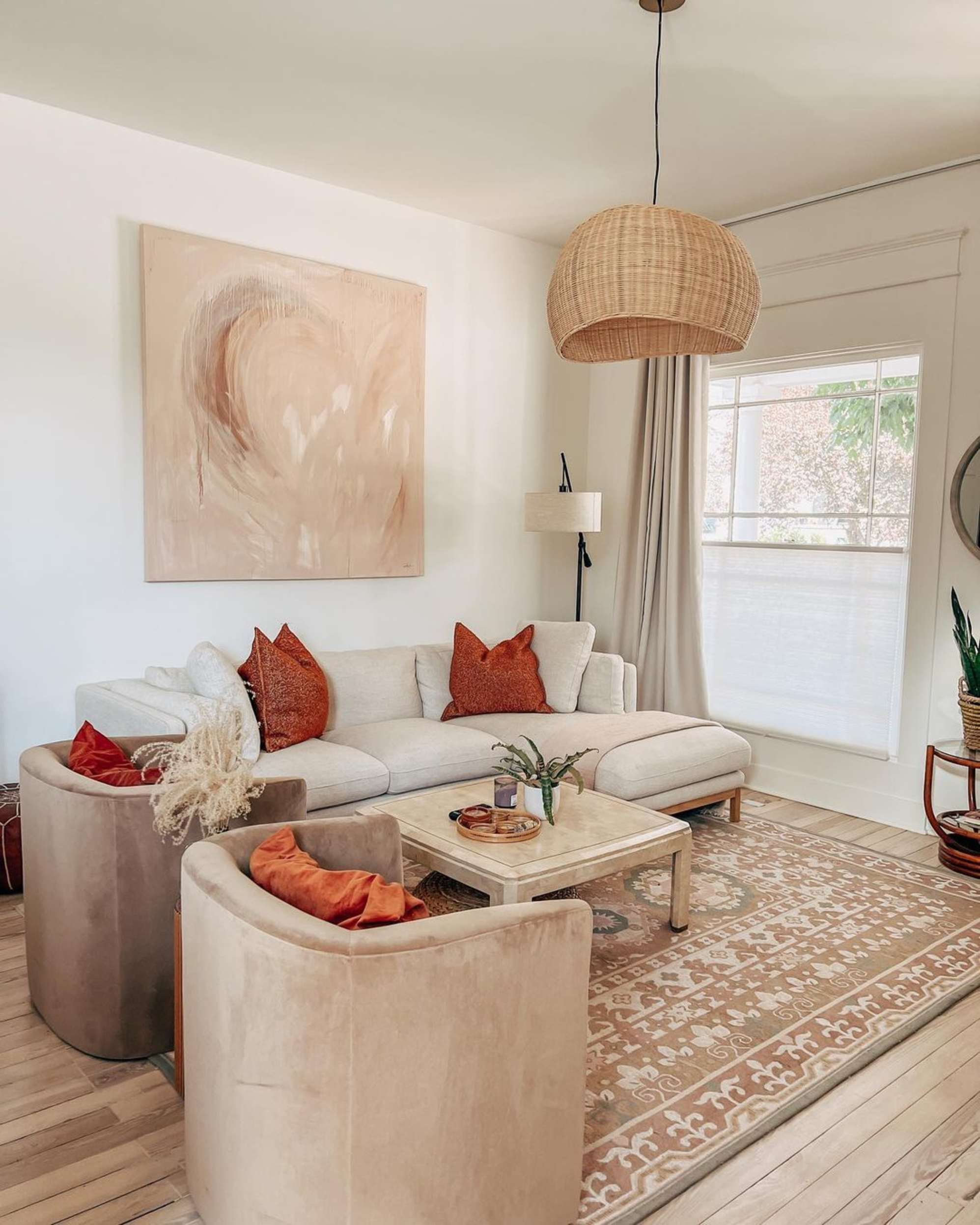 A sectional sofa, a coffee table, and two matching armchairs placed in a living room atop an area rug.