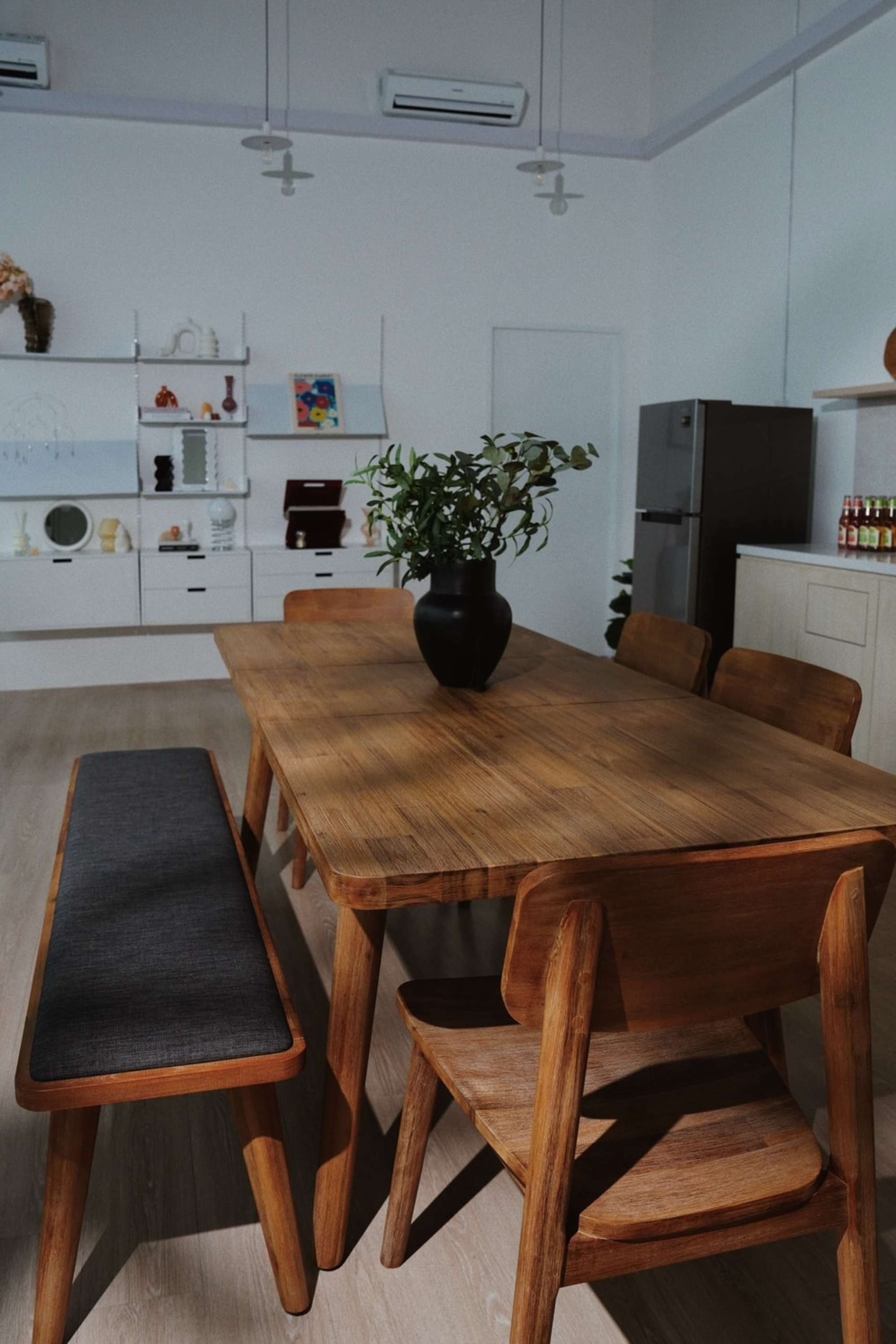 A wooden extendable dining table with matching chairs and a bench placed in the shared dining and kitchen space.