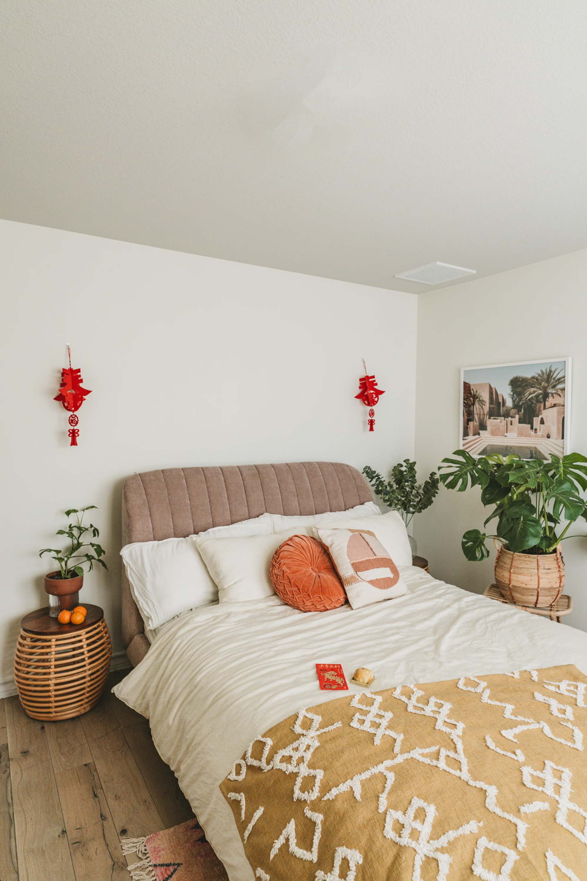 A tufted bed with white bedding and lunar new year decoration hanging on the walls.
