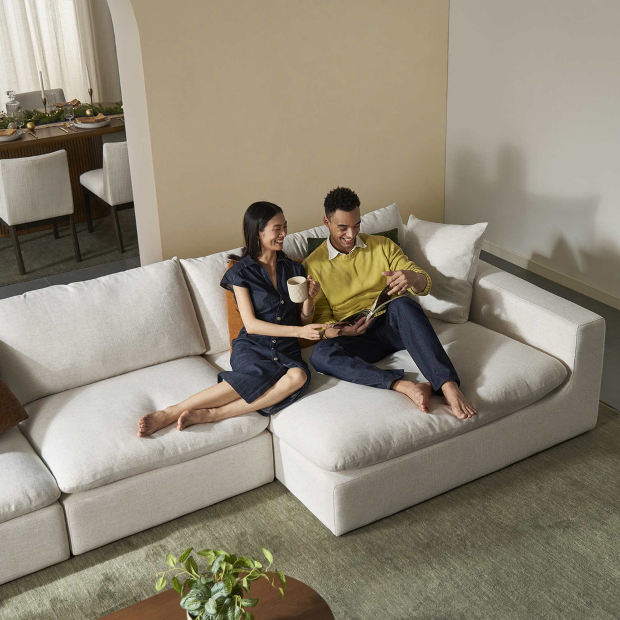 A couple sitting on a wide chaise sectional sofa.