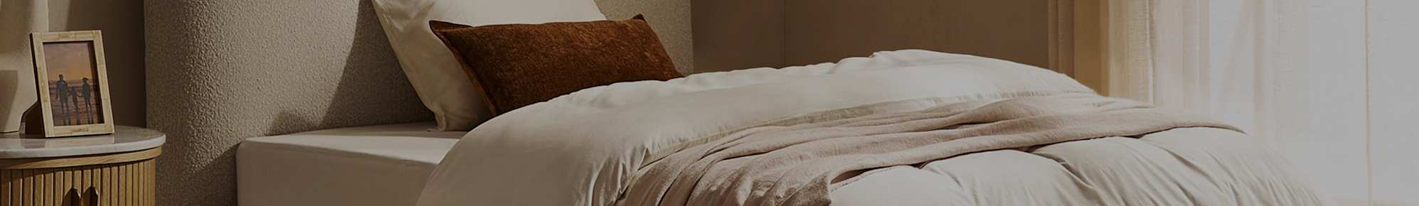 A bed with a brown throw cushion.