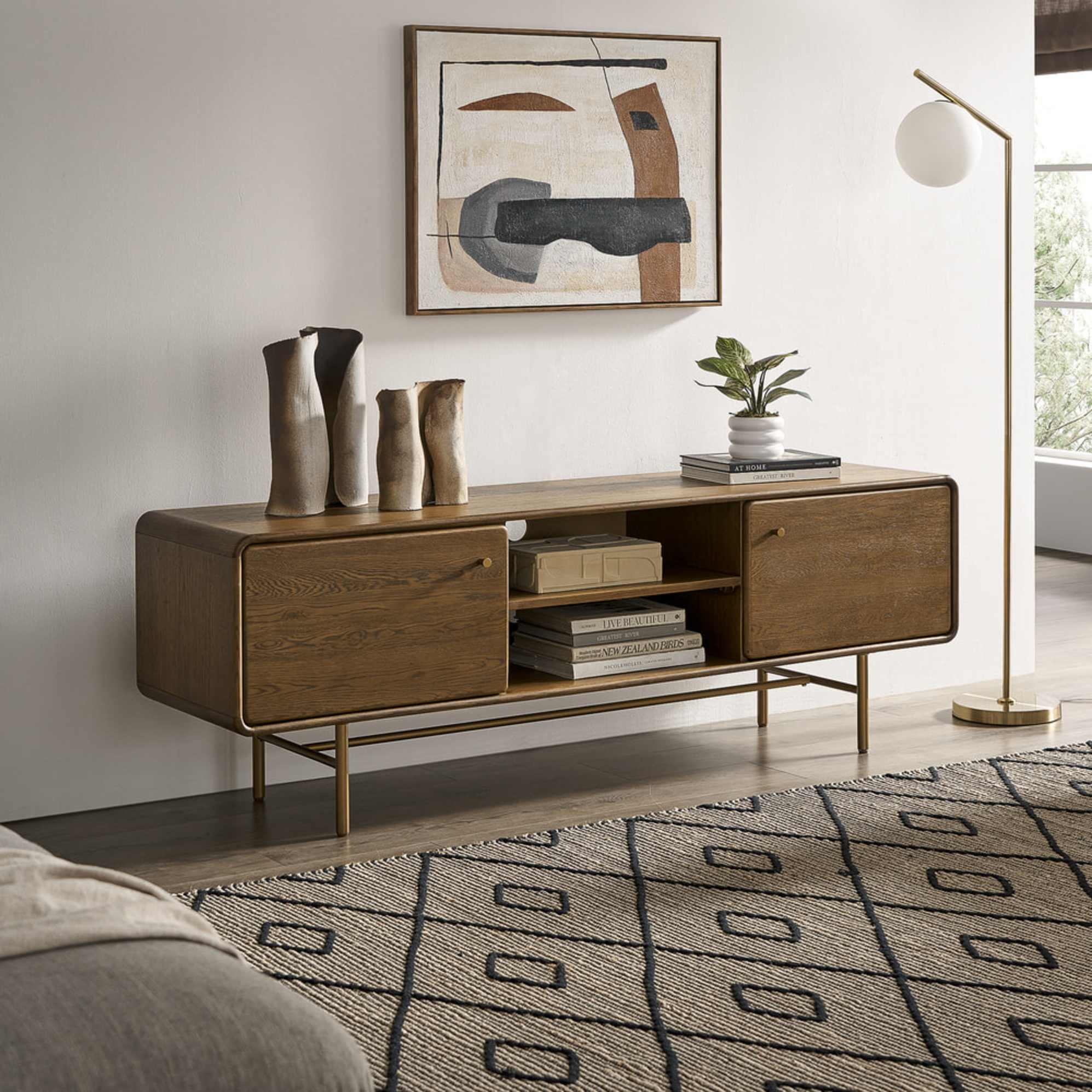 A wooden TV unit decorated with vases, books, and a potted plant.
