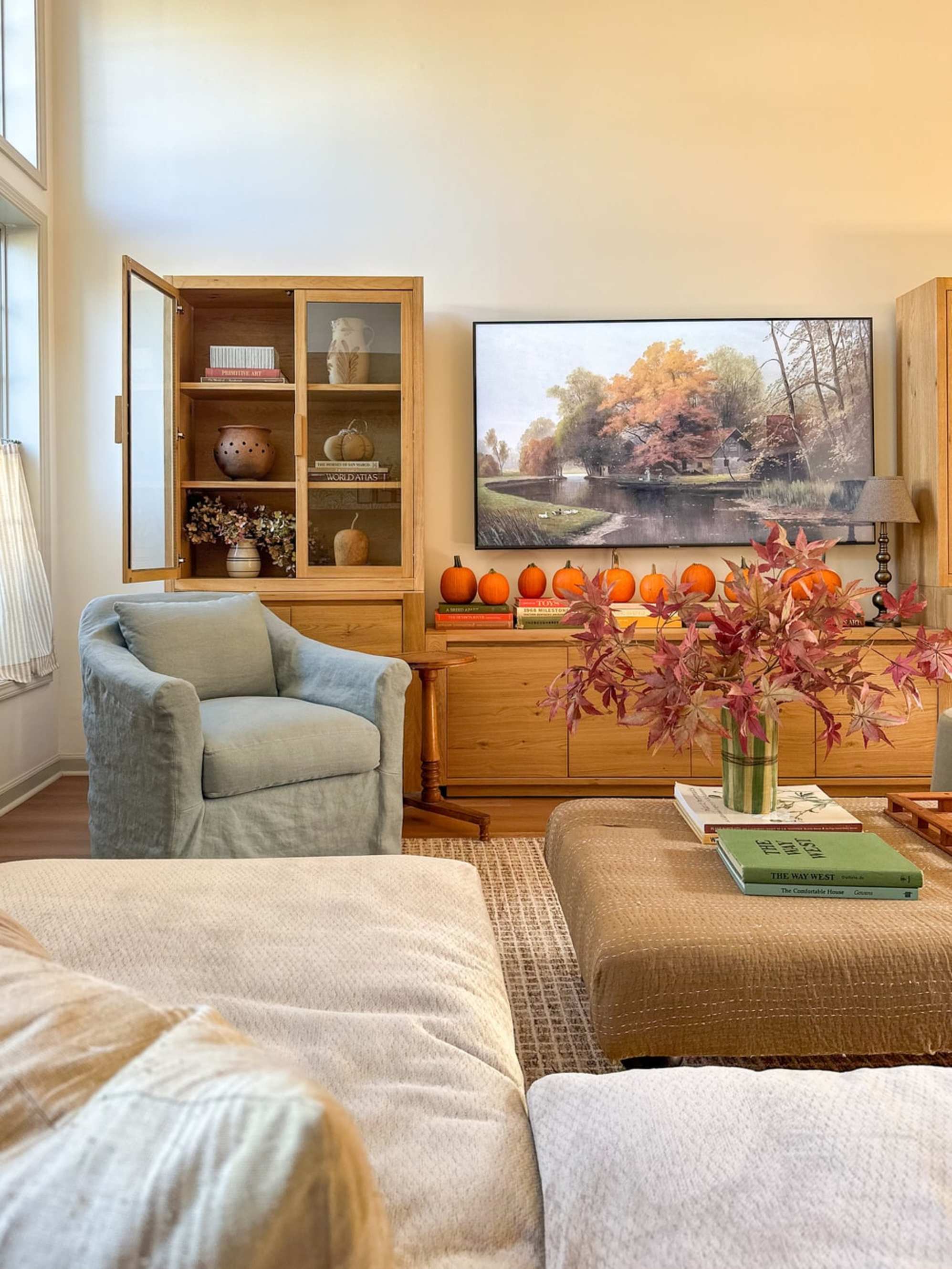 A wooden media storage system with one of its glass doors opened to reveal decor.