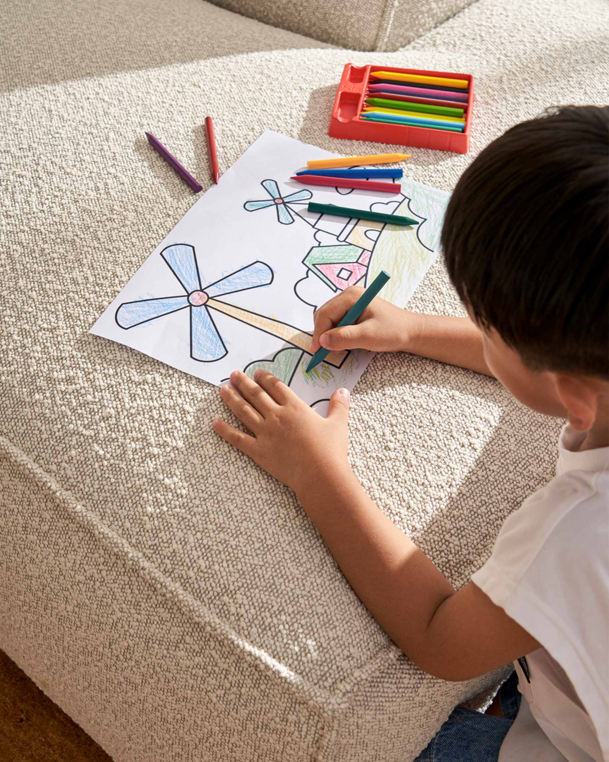 A child colouring on paper with crayons.